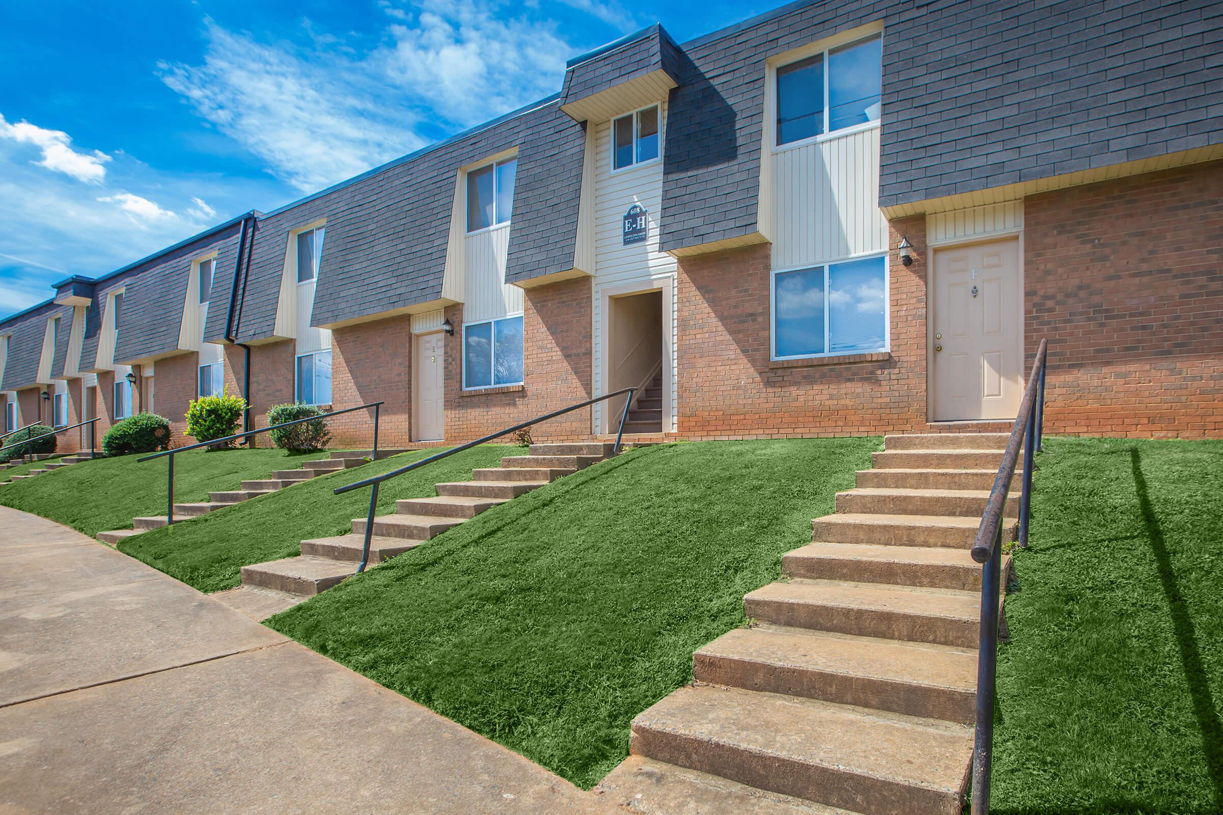 a large brick building with green grass