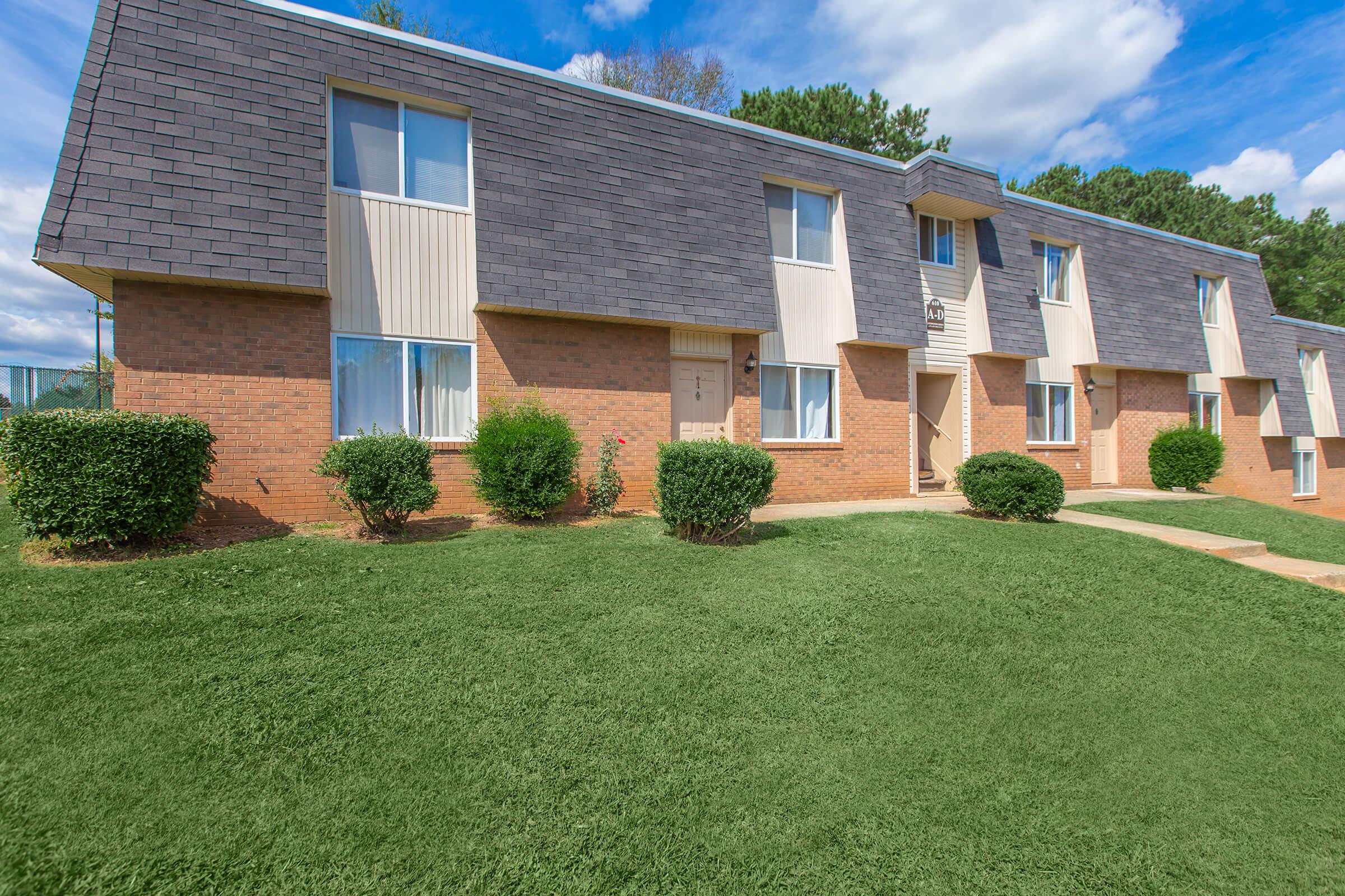 a large brick building with green grass in front of a house