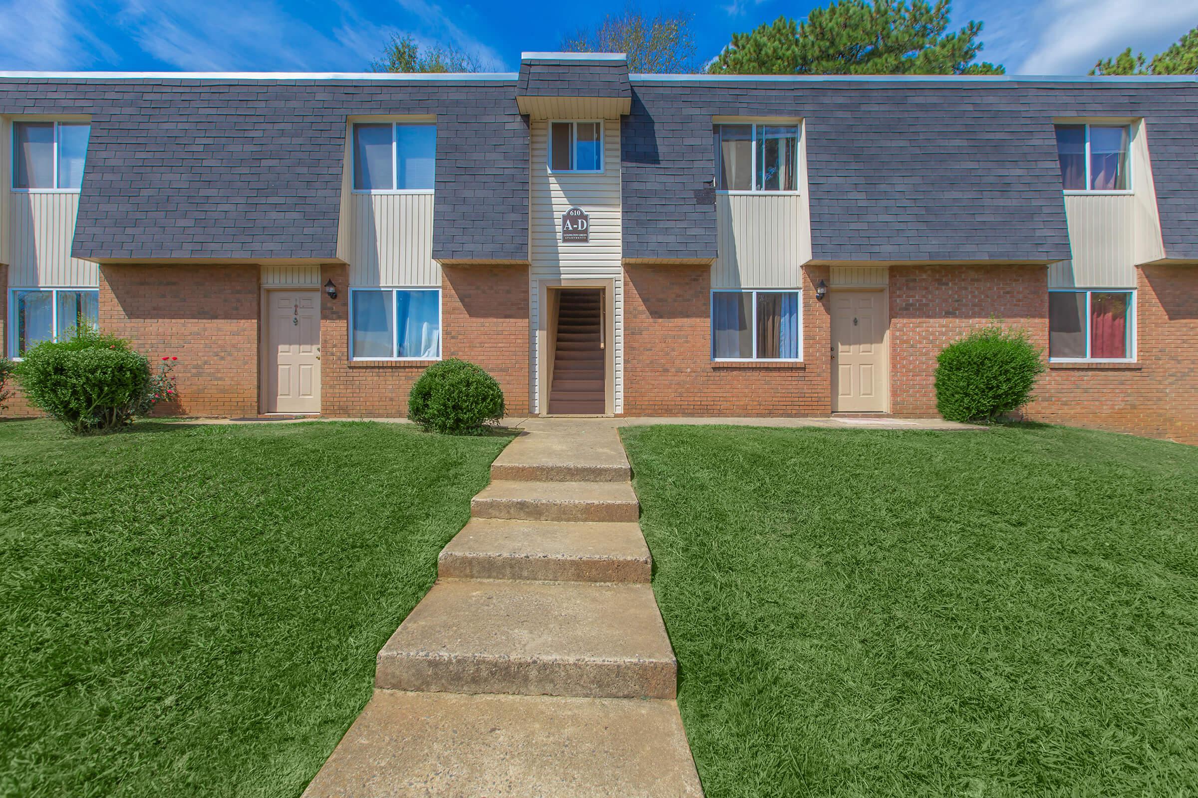 a house with a lawn in front of a brick building