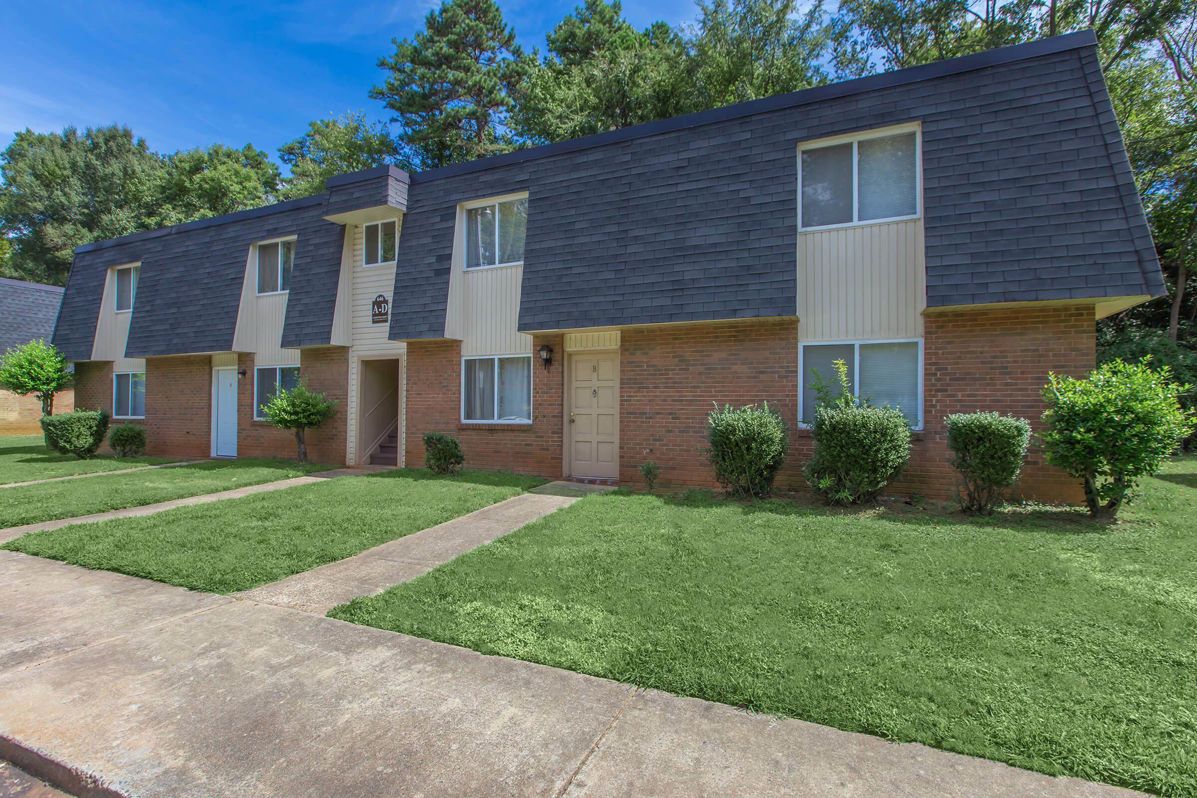 a large brick building with grass in front of a house