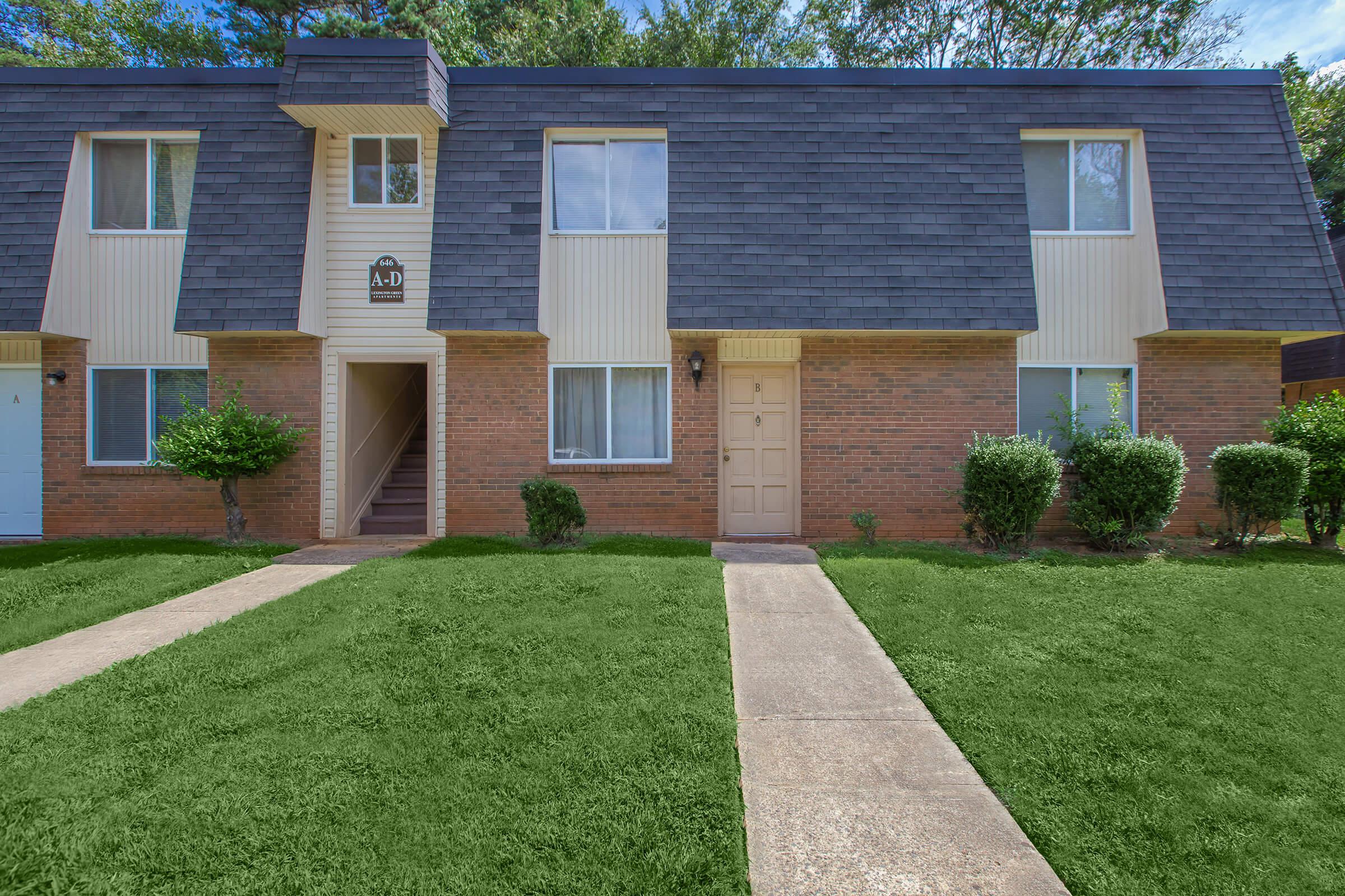 a house with a lawn in front of a brick building