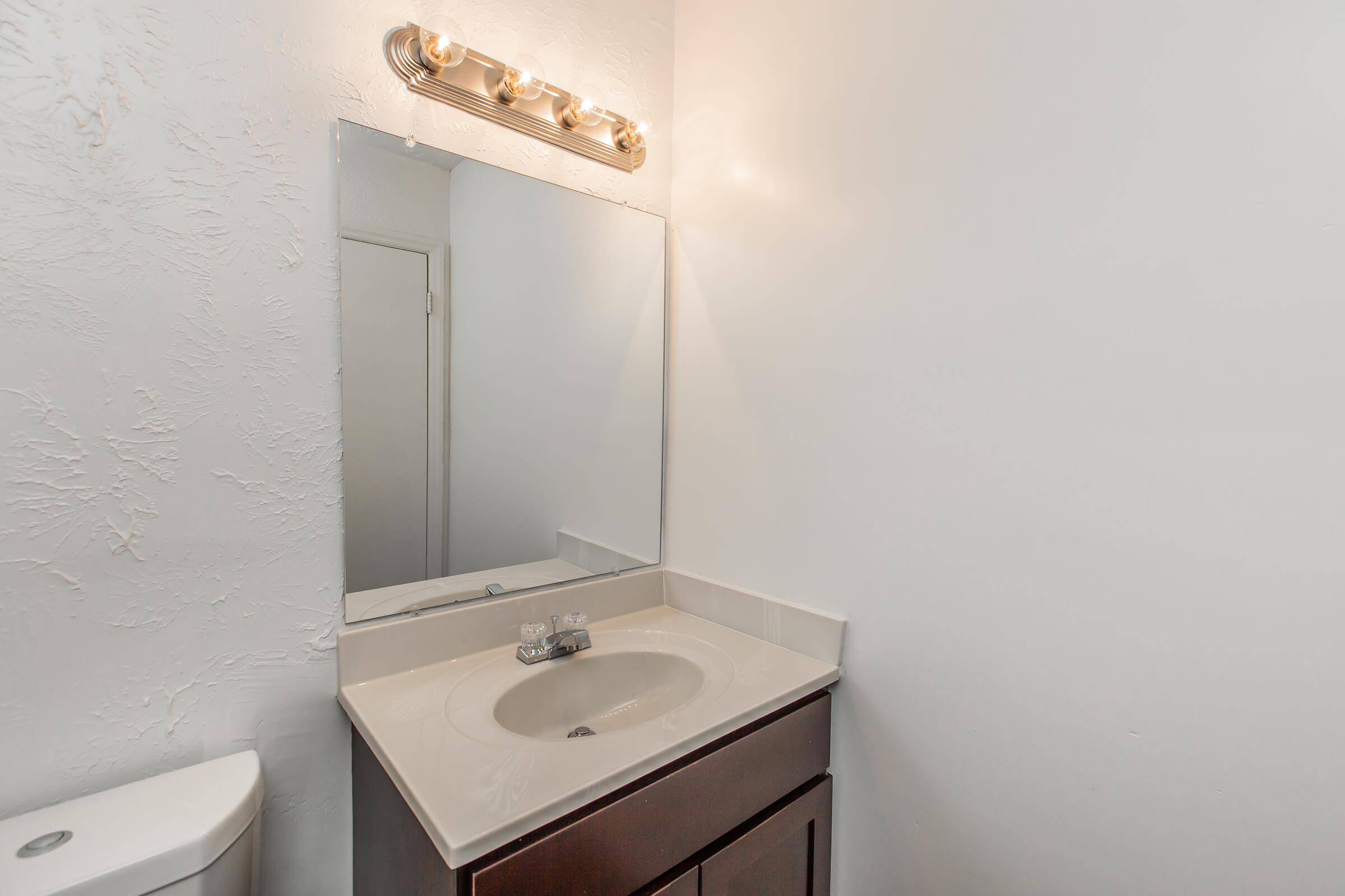 a white sink sitting under a mirror