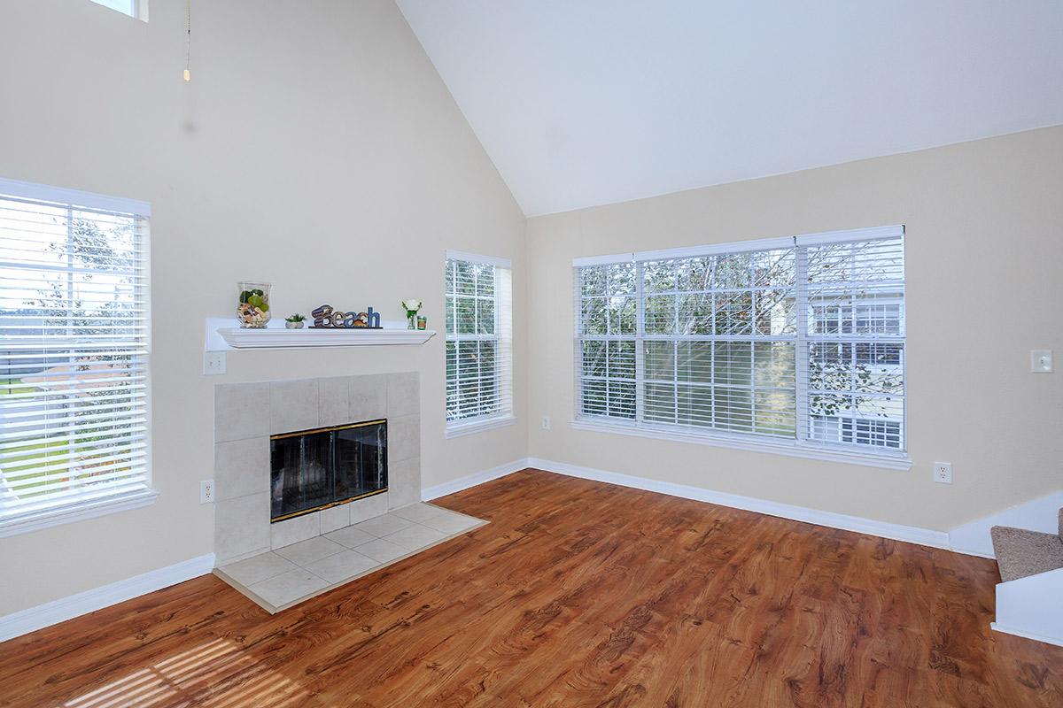 a living room with a wood floor next to a window