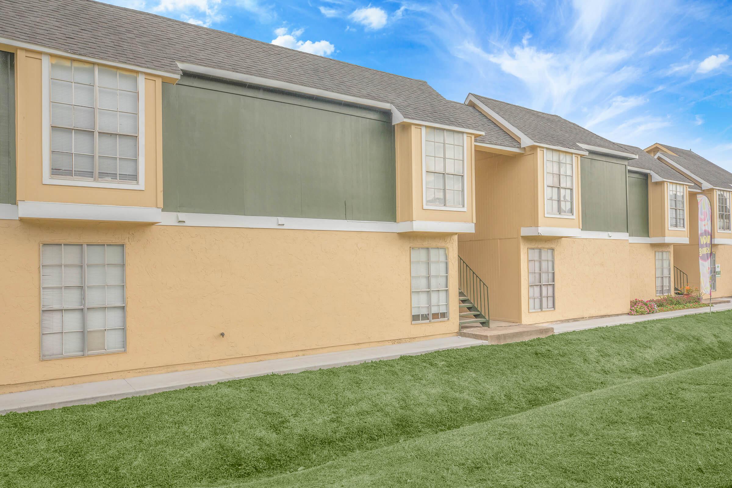 a large brick building with grass in front of a house