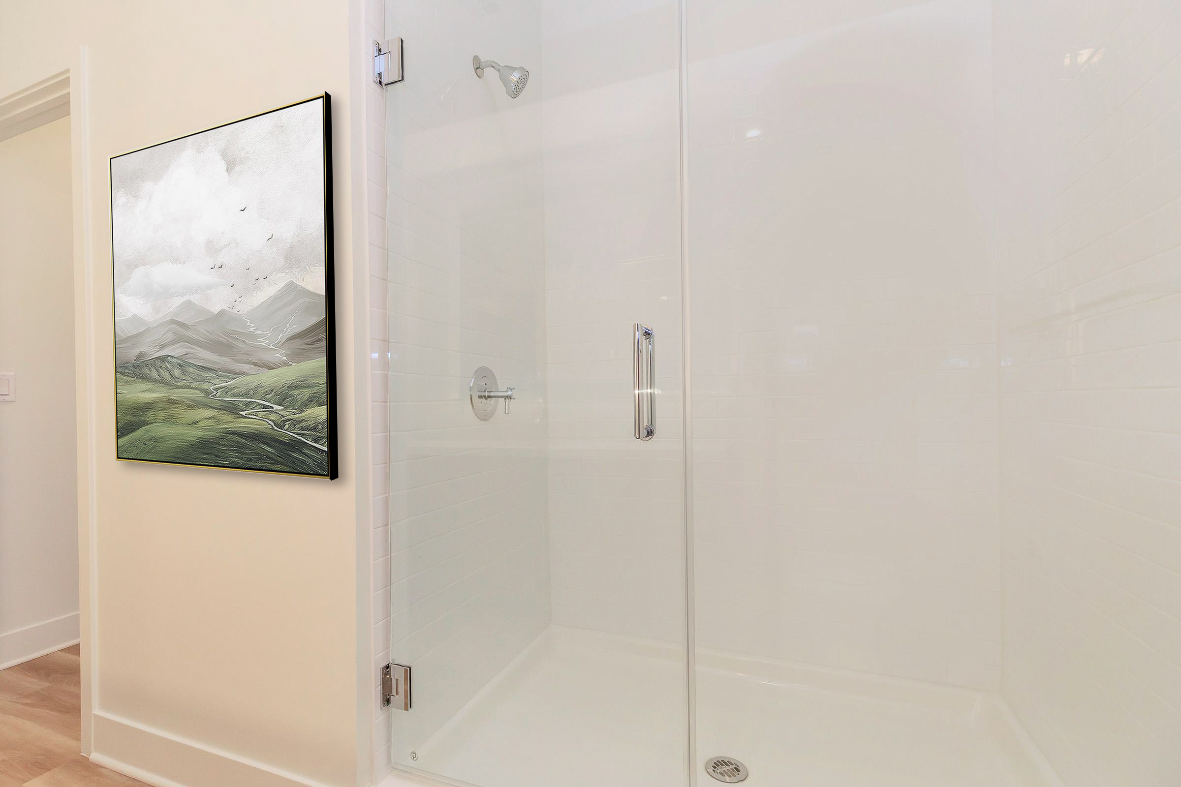 A modern bathroom featuring a clear glass shower enclosure and a framed artwork on the wall depicting a serene landscape with mountains and clouds. The walls are light-colored, and the floor is wooden, creating a bright and airy atmosphere.