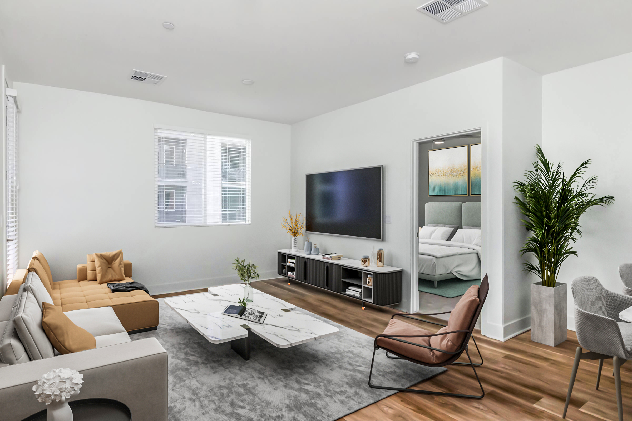 A modern living room featuring a beige and white sectional sofa, a marble coffee table, and a large flat-screen TV mounted on a dark media console. There’s a stylish plant in the corner, light hardwood floors, and a dining area with a gray chair and table. A door leads to a bedroom in the background with soft lighting.