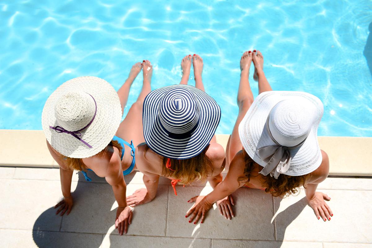 Young woman sun hat sitting poolside resort pool summer holiday iStock-636409474.jpg