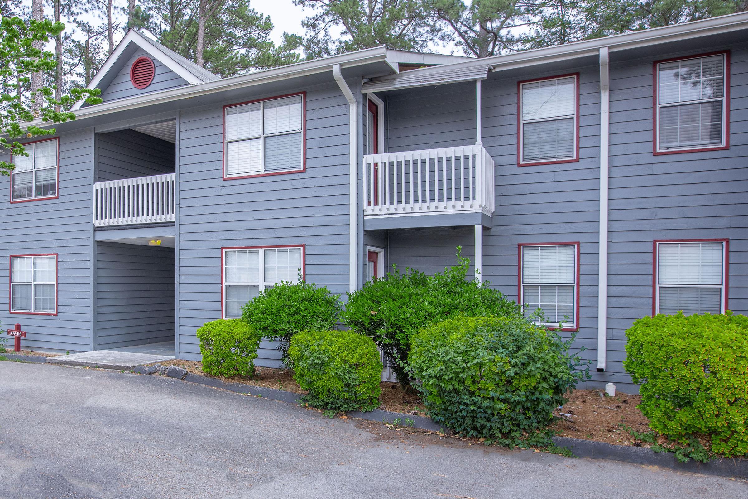 a house with bushes in front of a brick building