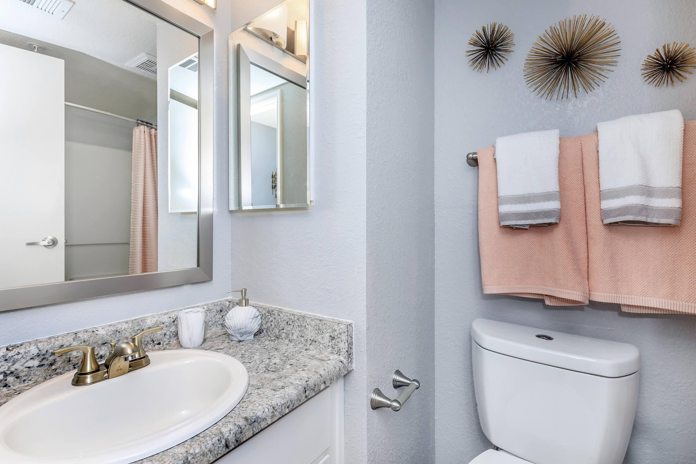 a white sink sitting under a mirror