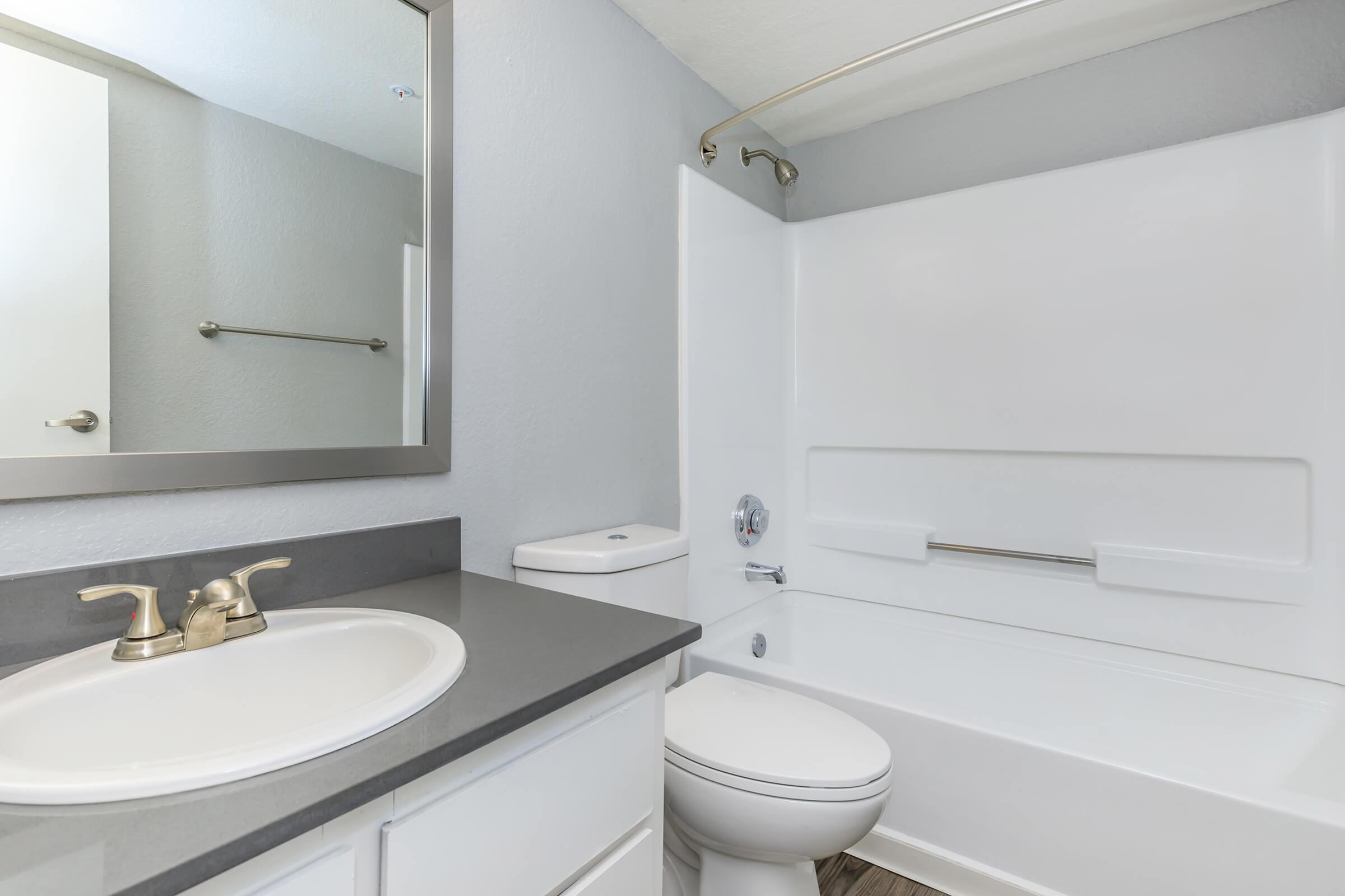 a white sink sitting under a mirror