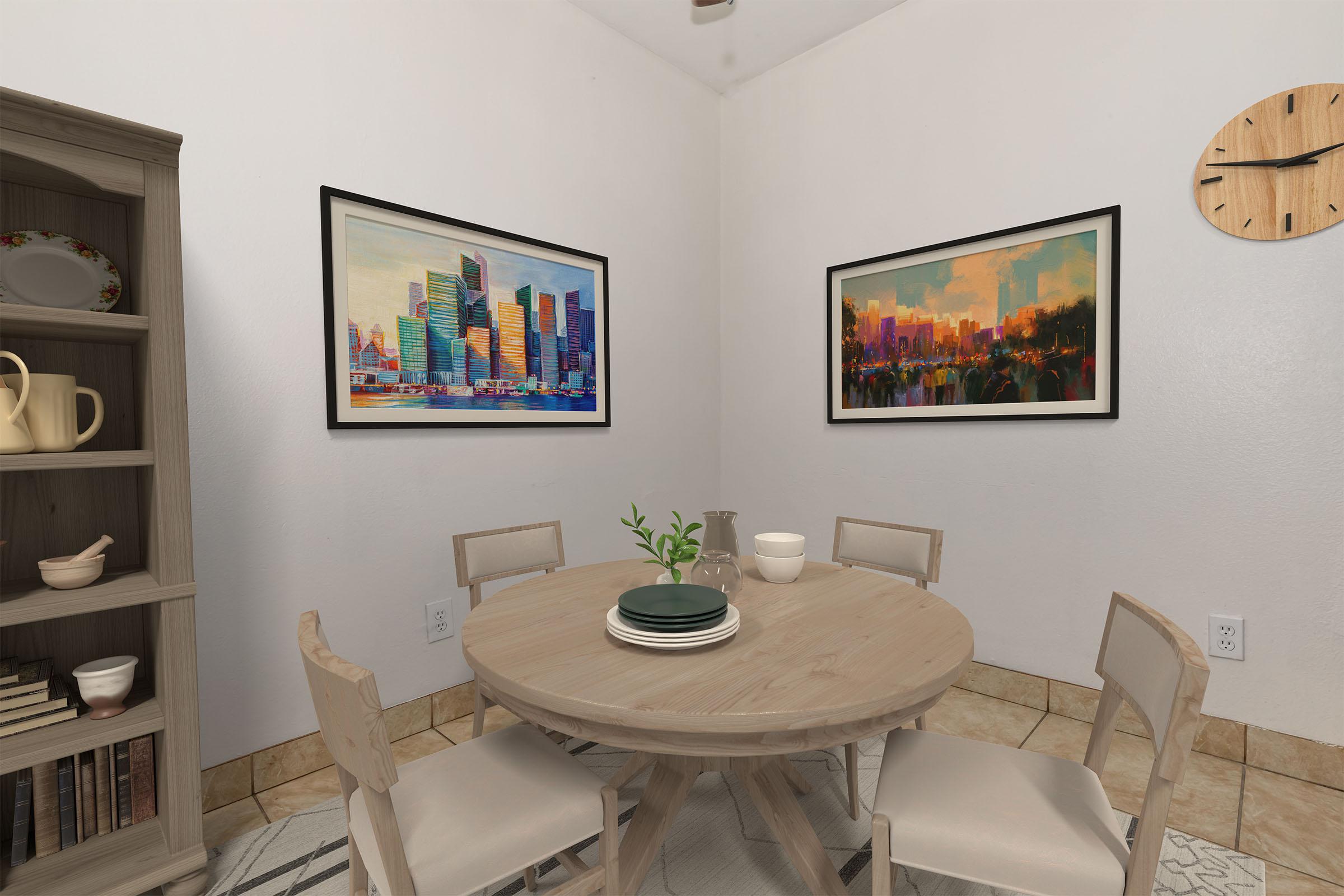 A cozy dining area featuring a round wooden table set with plates and a small plant centerpiece. Two framed artworks hang on the white walls, showcasing cityscapes. A wooden shelf in the background displays dishes and books, with a clock on the wall adding a homey touch. The floor has a subtle patterned rug.