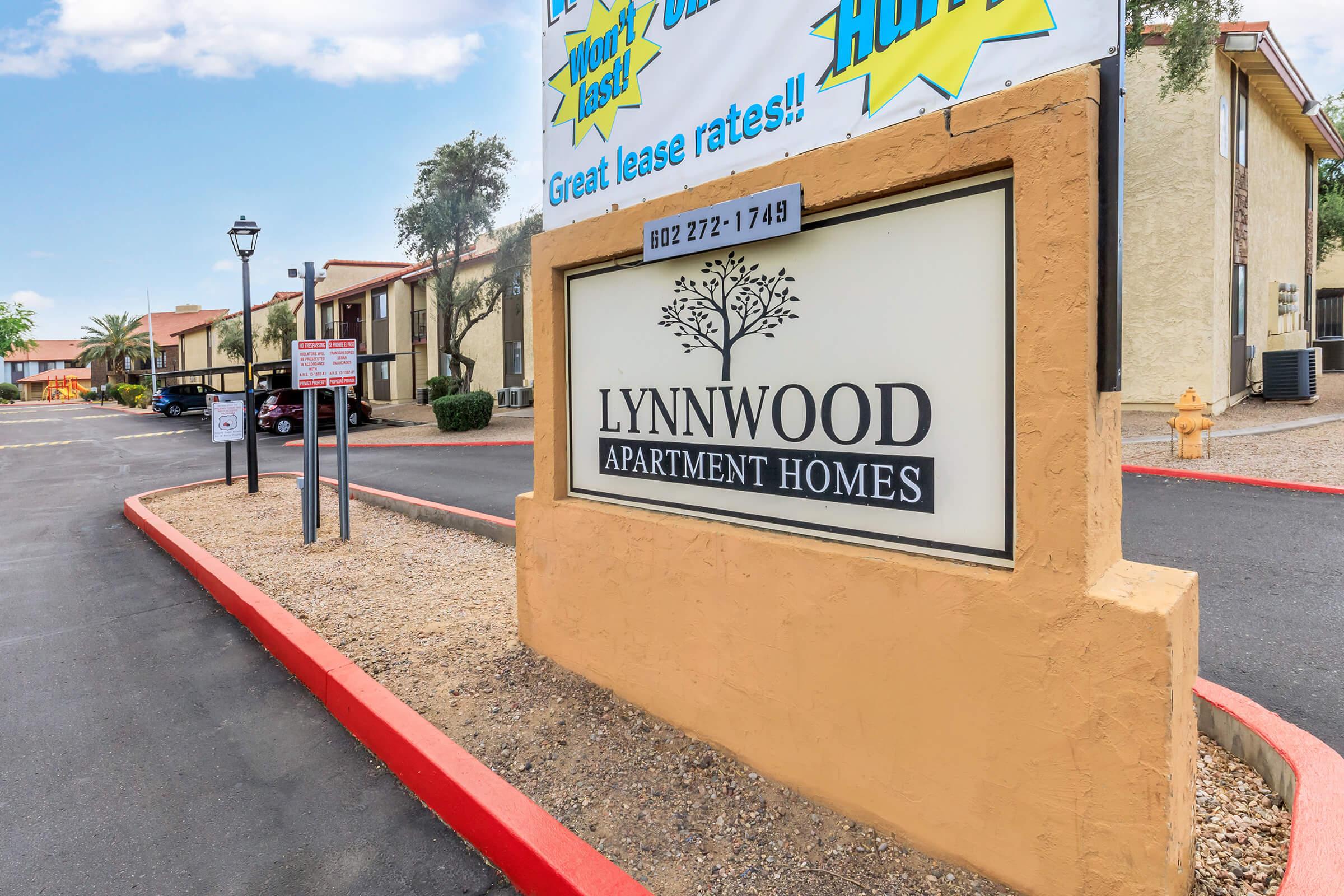 Sign for Lynnwood Apartment Homes showing contact information and a promotion for great lease rates. Surrounding area features landscaping and a clear blue sky.