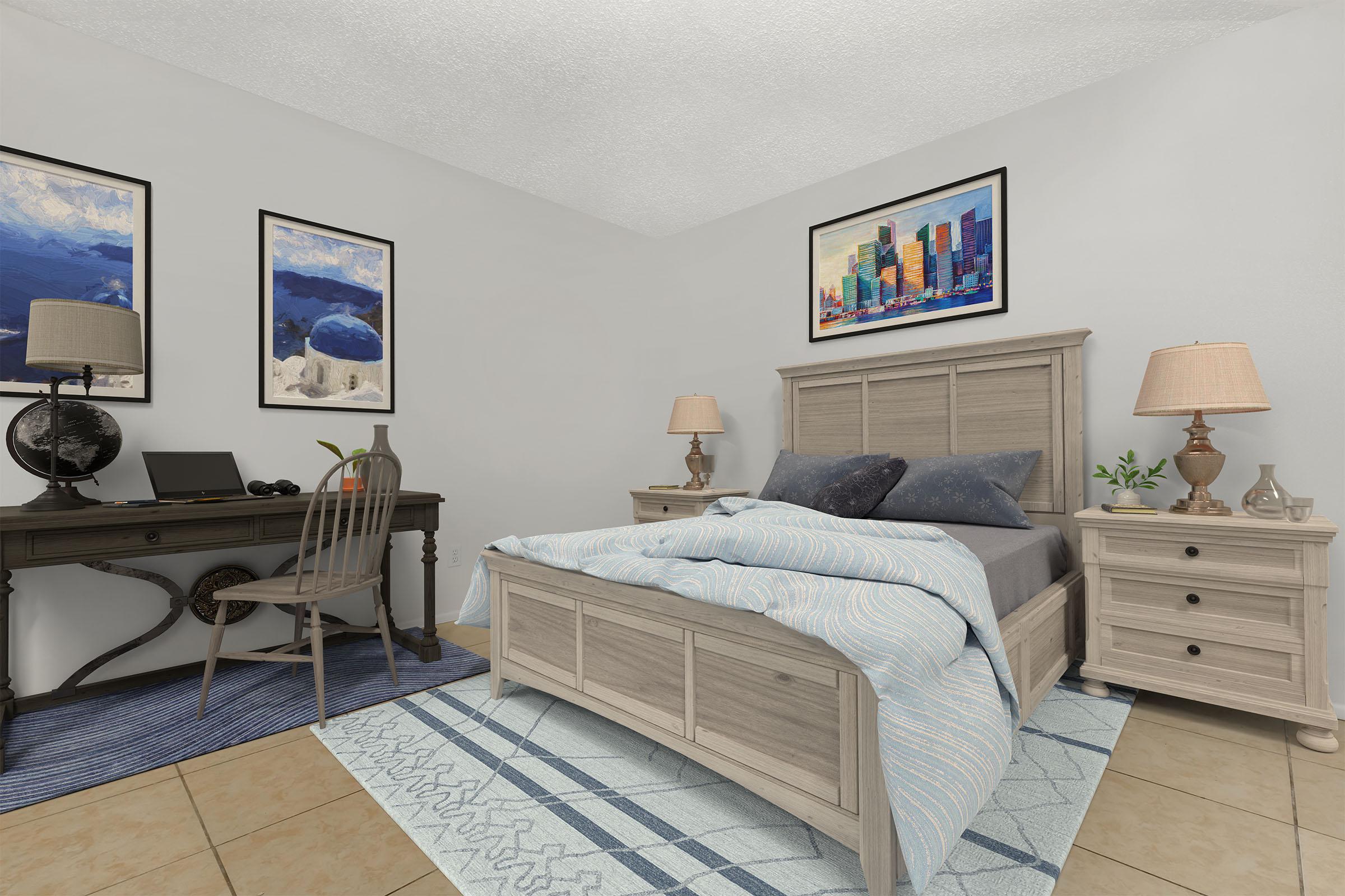 A cozy bedroom featuring a light wood bed with blue and white bedding, two bedside lamps, and framed artwork on the walls. A wooden desk with a chair is positioned against one wall, showcasing a globe and a small decorative plant. The room has warm, neutral tones and a patterned rug.