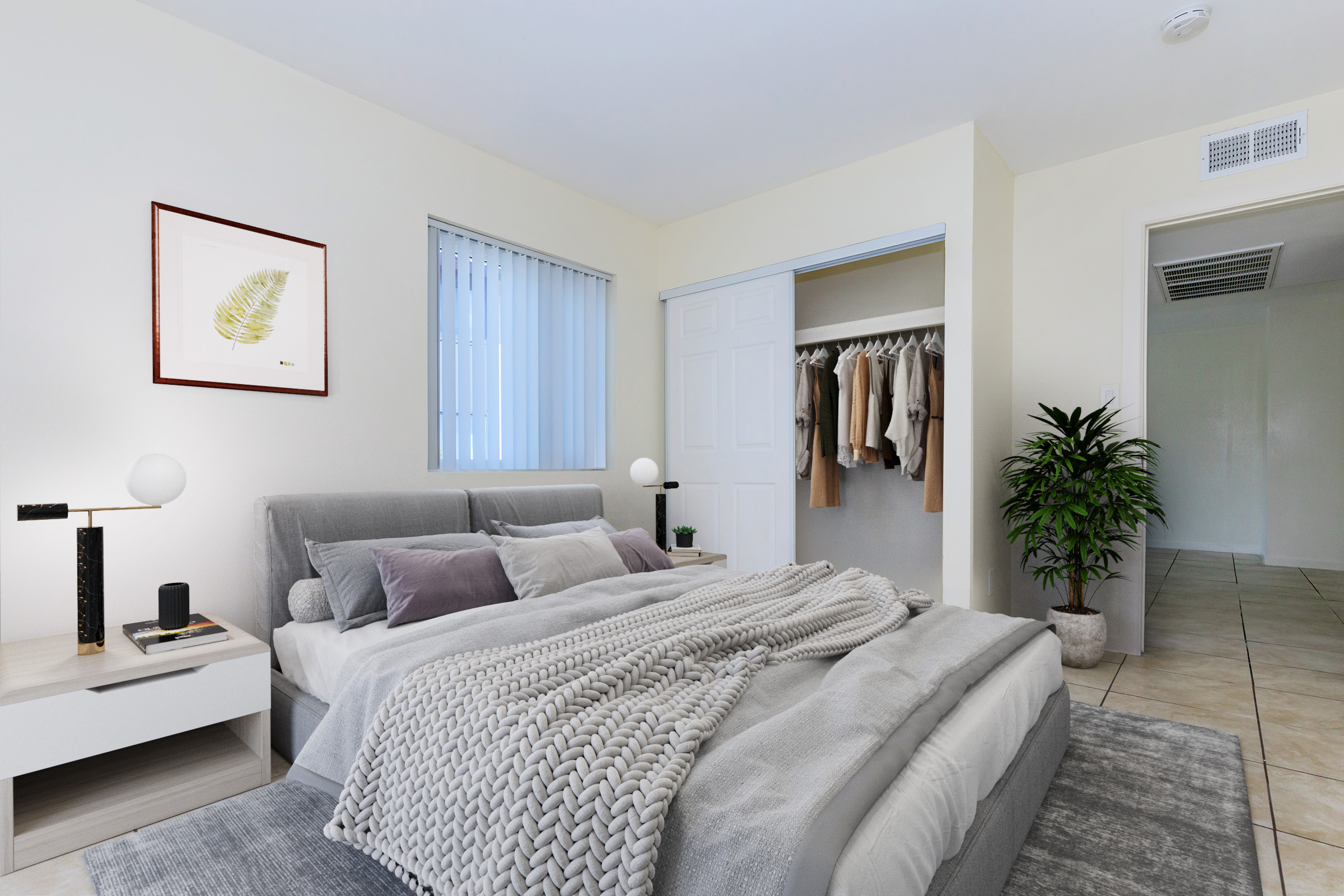 A modern bedroom featuring a queen-sized bed with gray bedding, decorative pillows, and a cozy throw. There's a nightstand with a lamp and an alarm clock. A closet is open with hanging clothes, and a potted plant adds greenery. Light-colored walls and tiled flooring enhance the spacious feel of the room.