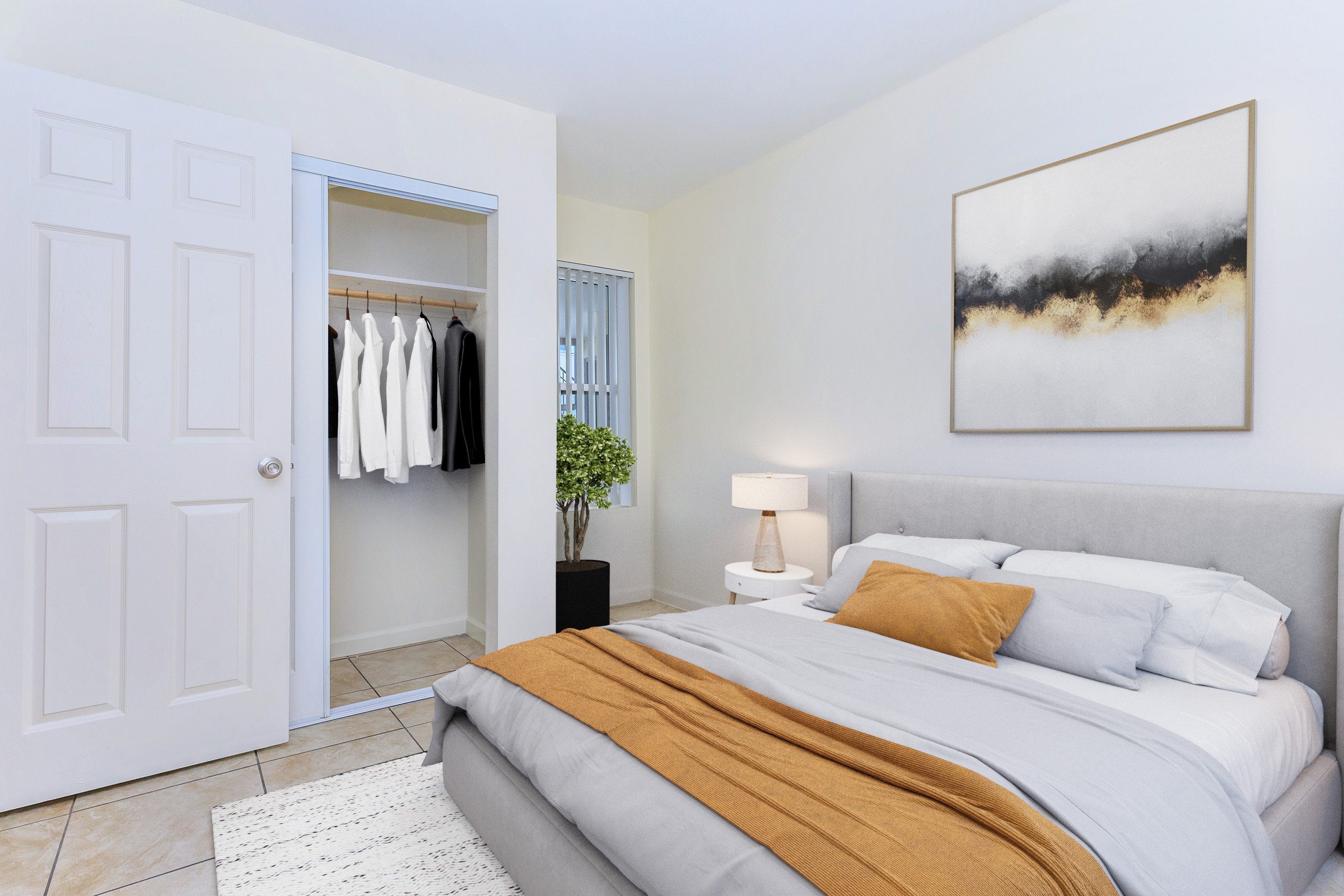 A cozy bedroom featuring a light gray bed with white and orange linens. There's a bedside lamp on a round table, a closet with hanging clothes, and a decorative plant. The walls are painted a soft color, and there's a modern artwork above the bed, creating a warm and inviting atmosphere.