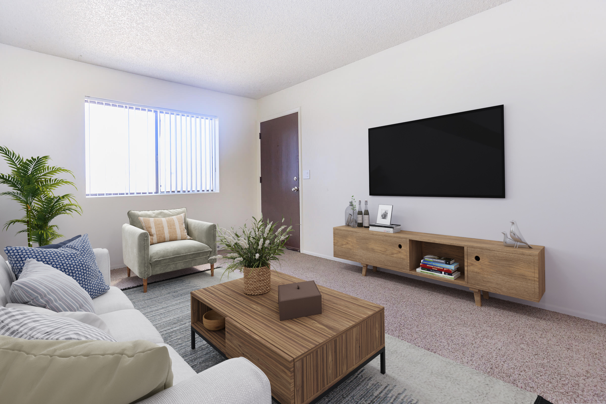 A modern living room featuring a light-colored sofa with patterned cushions, a wooden coffee table, and a wooden TV stand with decorative items. A green armchair is placed near a window with horizontal blinds. A potted plant adds a touch of greenery, and the walls are painted a neutral color.