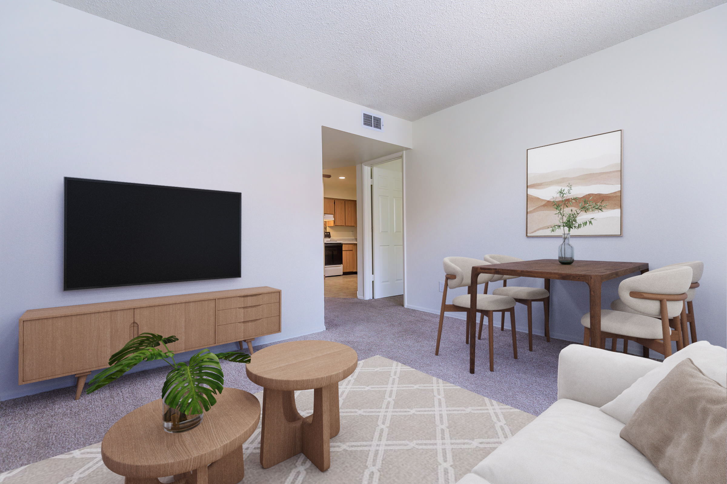 A modern living room featuring a light color scheme. It includes a flat-screen TV on a wooden media console, a round coffee table, a cozy white sofa, and a dining area with a wooden table and chairs. Decorative elements include a potted plant and artwork on the wall, creating a warm and inviting atmosphere.