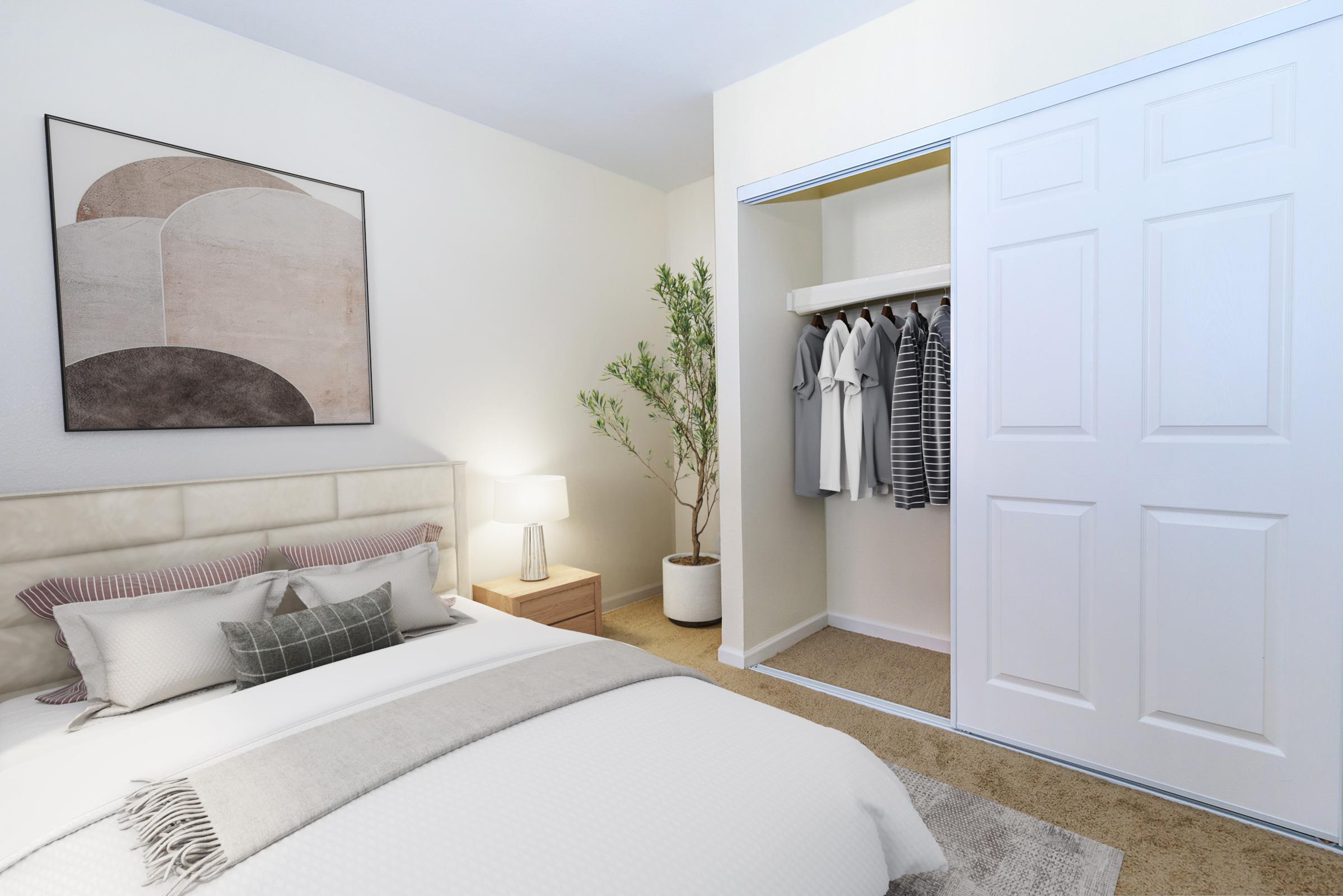 A cozy bedroom featuring a comfortable bed with decorative pillows, a bedside lamp, and a stylish wall art piece. There's a closet with neatly hung clothes and a potted plant in the corner, creating a warm and inviting atmosphere. Soft neutral colors are used throughout the space.