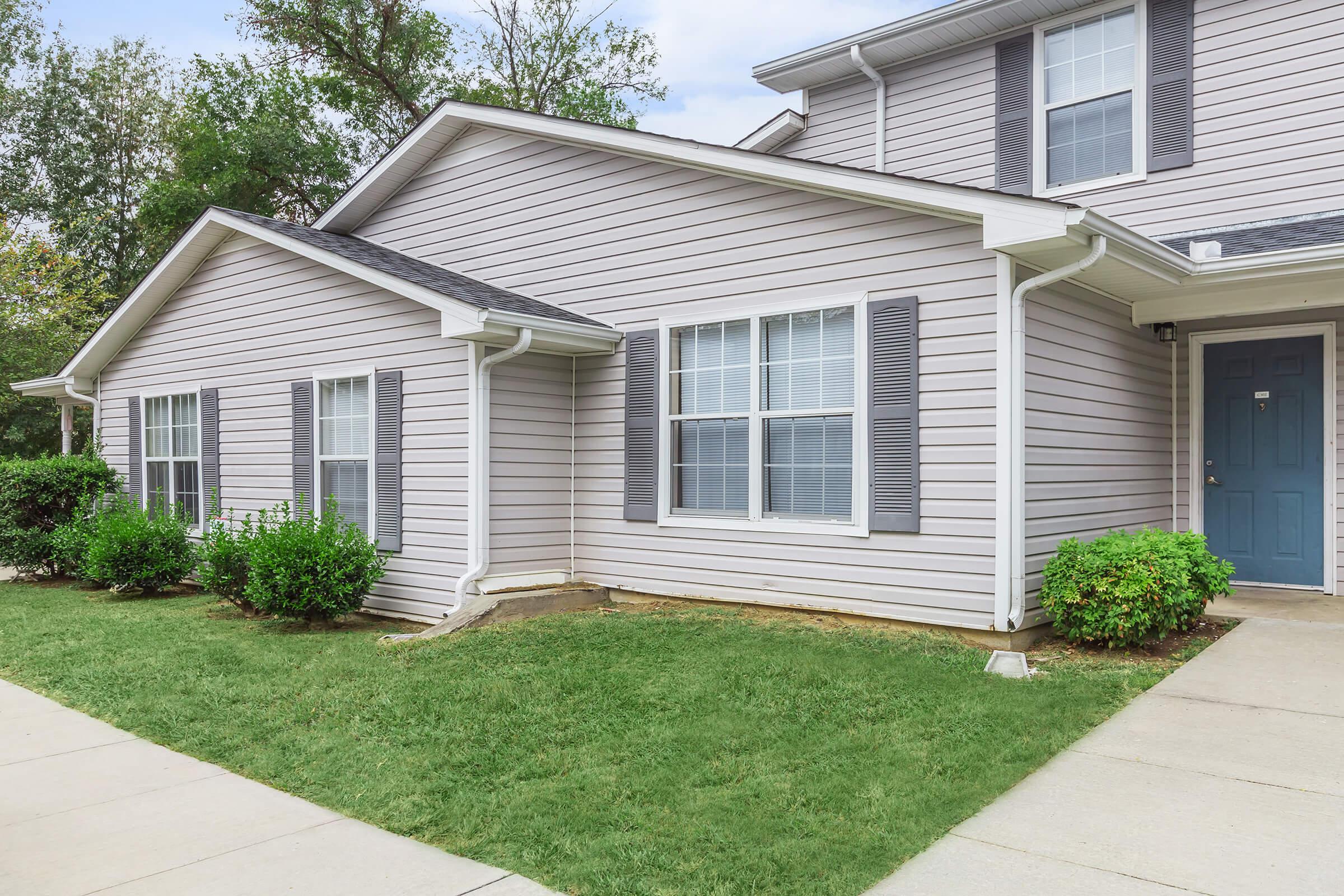 a house with a lawn in front of a brick building