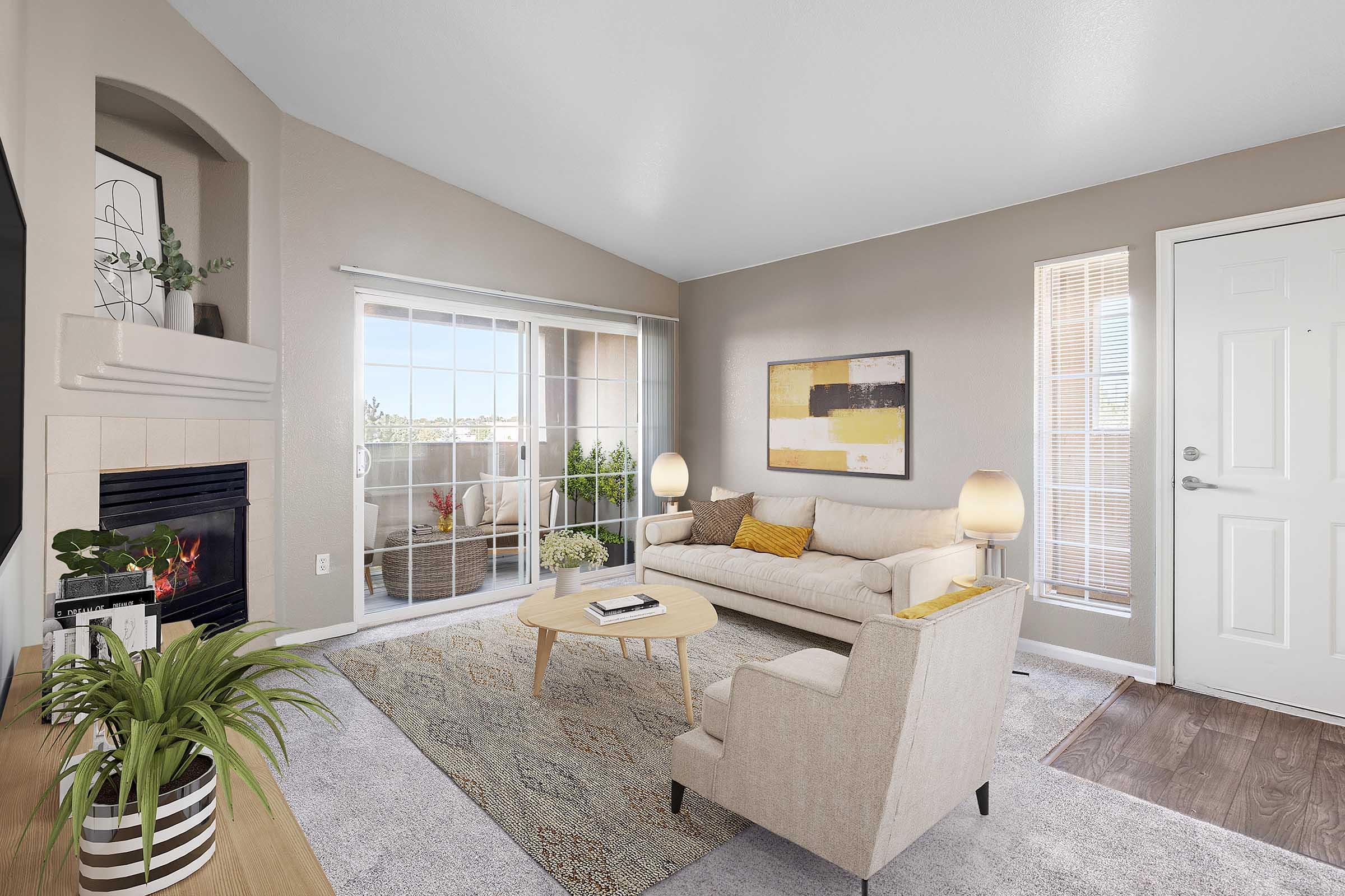 A cozy living room featuring a light-colored sofa, a small round coffee table, and a comfortable armchair. There is a fireplace on the left, a large window with natural light, and a door on the right. Decor includes a plant and abstract wall art, creating a welcoming and modern atmosphere.