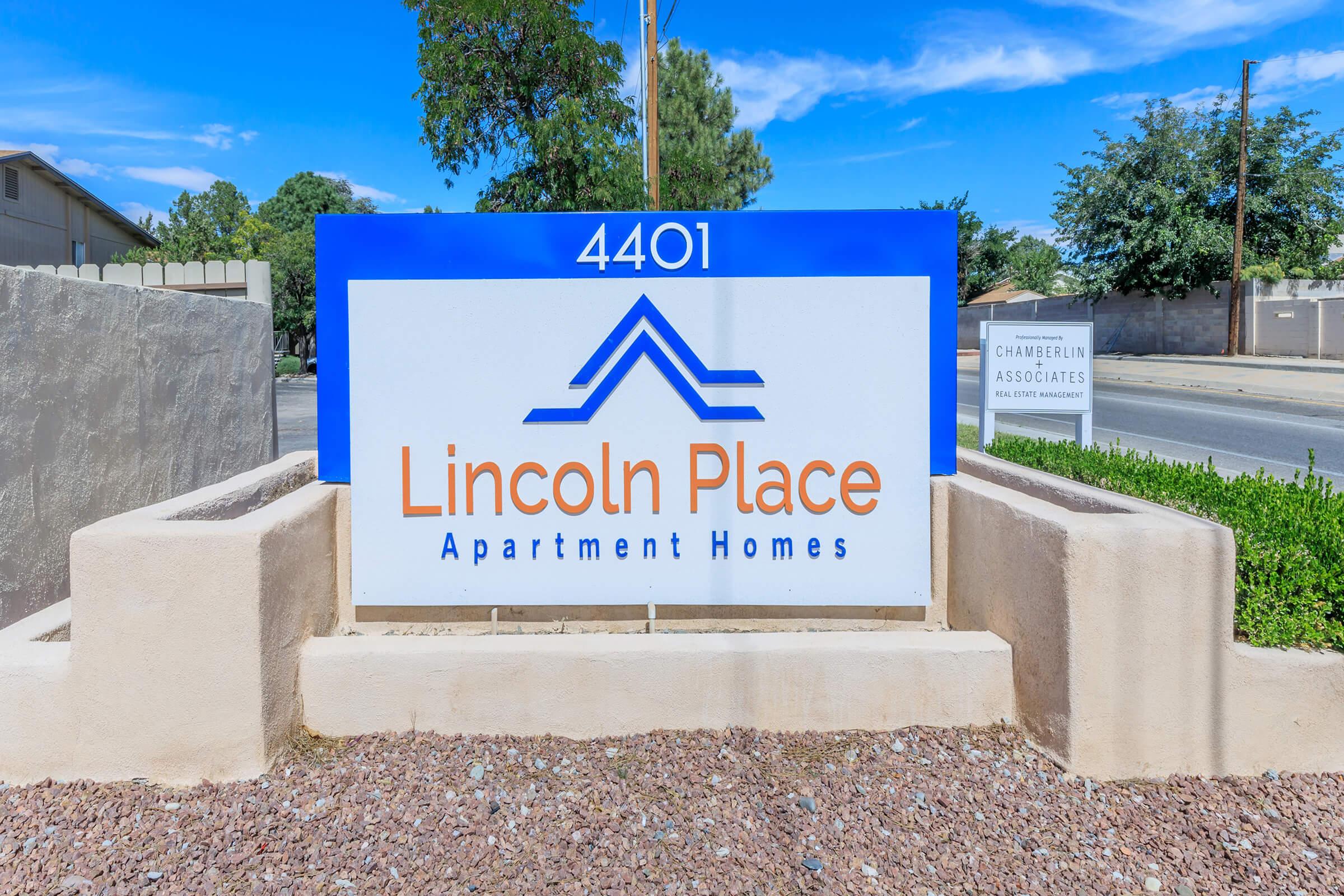 Sign for Lincoln Place Apartment Homes, featuring the address "4401" prominently displayed. The sign includes a stylized mountain or roof graphic above the text. Surrounding landscaping and a street view are visible in the background.