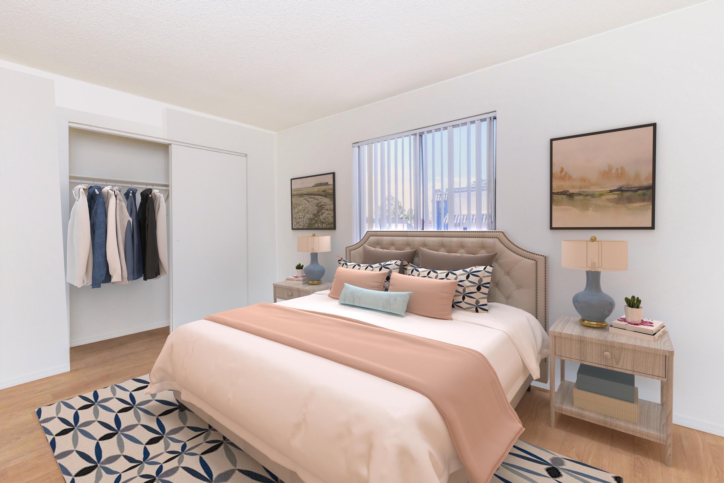 A beautifully designed bedroom featuring a cozy bed with soft bedding in peach and white tones, two decorative pillows, and a stylish headboard. There's a wooden nightstand with a lamp, and framed artwork on the walls. A closet with hanging clothes is visible, along with a patterned rug on the floor.