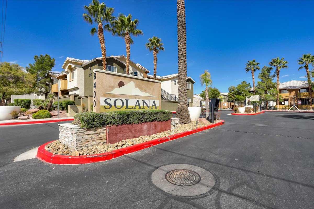 Sign for Solana community featuring palm trees and landscaped surroundings. The entrance is marked by a decorative stone monument with the name "SOLANA" prominently displayed. The area has clear blue skies and a well-maintained road.