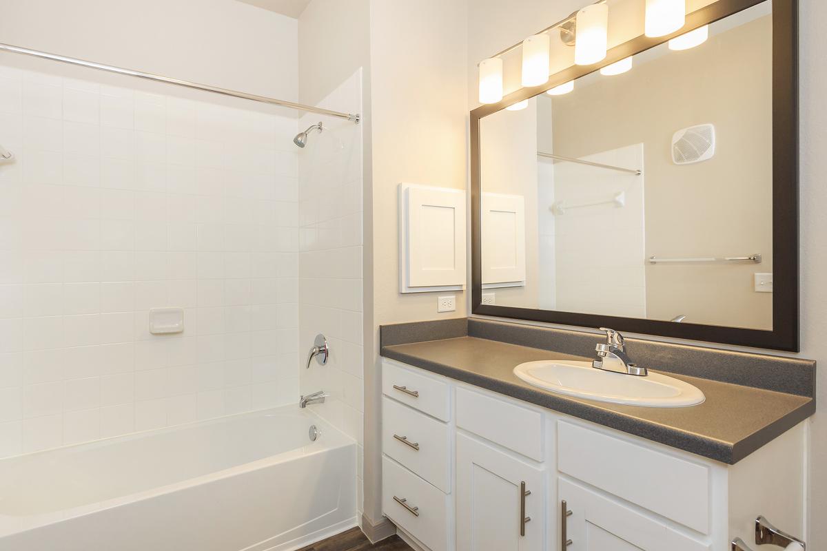 a white sink sitting under a mirror