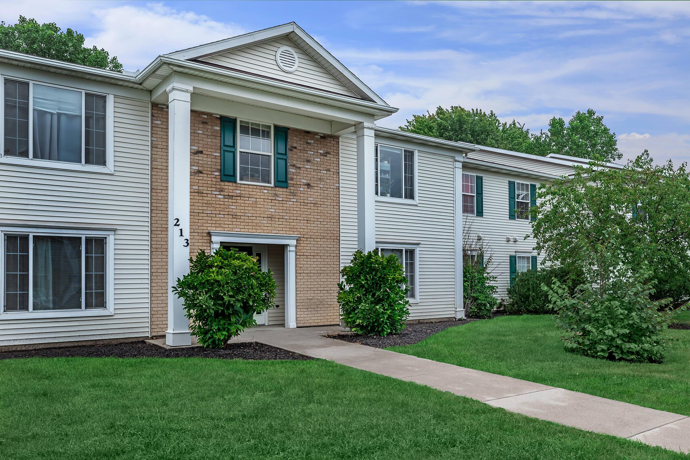 a house with a lawn in front of a brick building