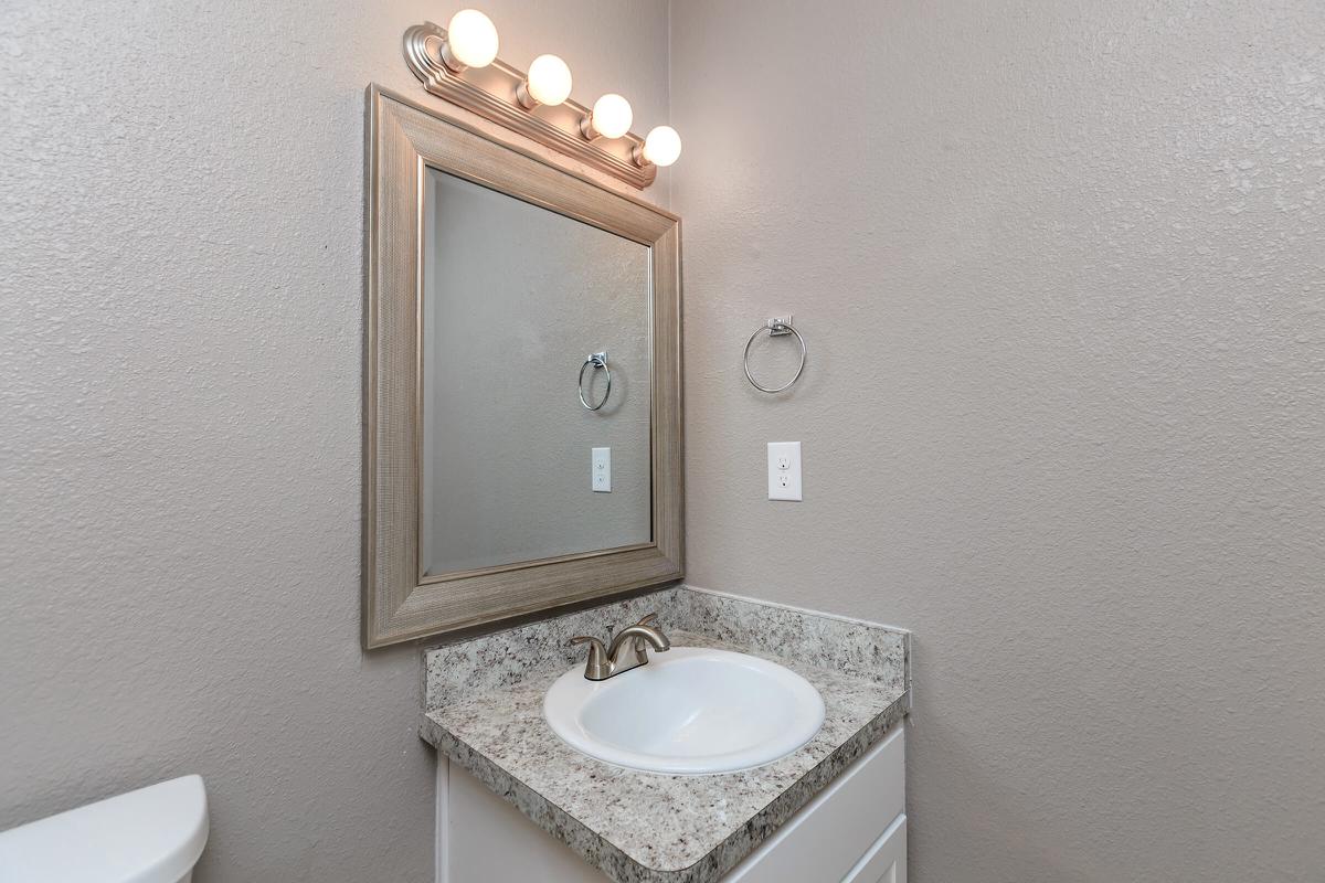 a white sink sitting under a mirror