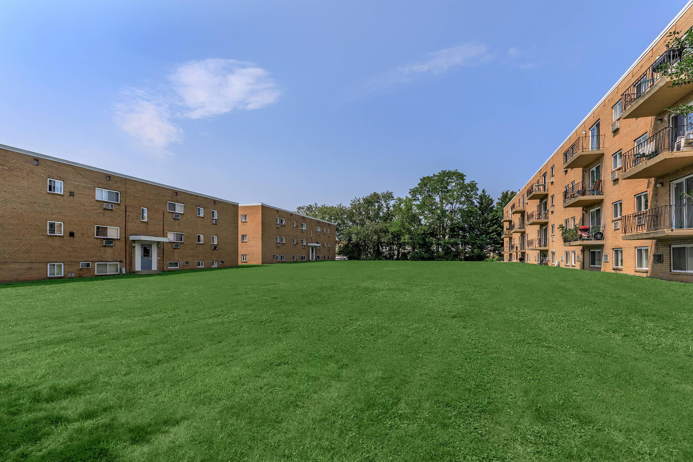 a large brick building with a grassy field