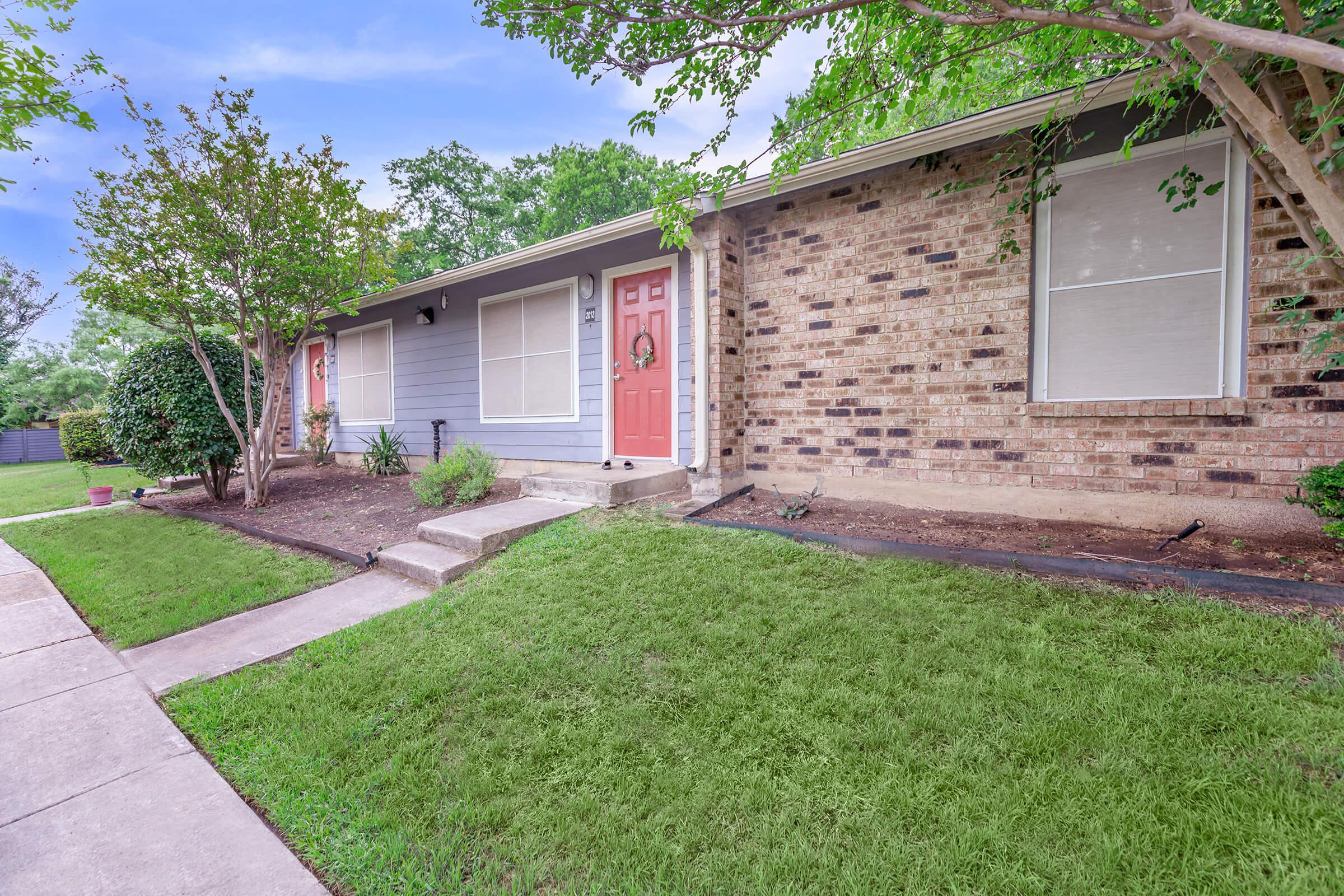 a house with a lawn in front of a brick building