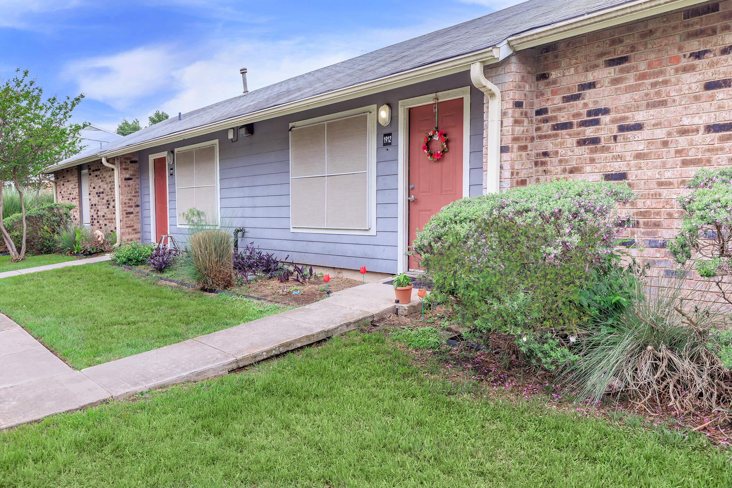 a large brick building with grass in front of a house