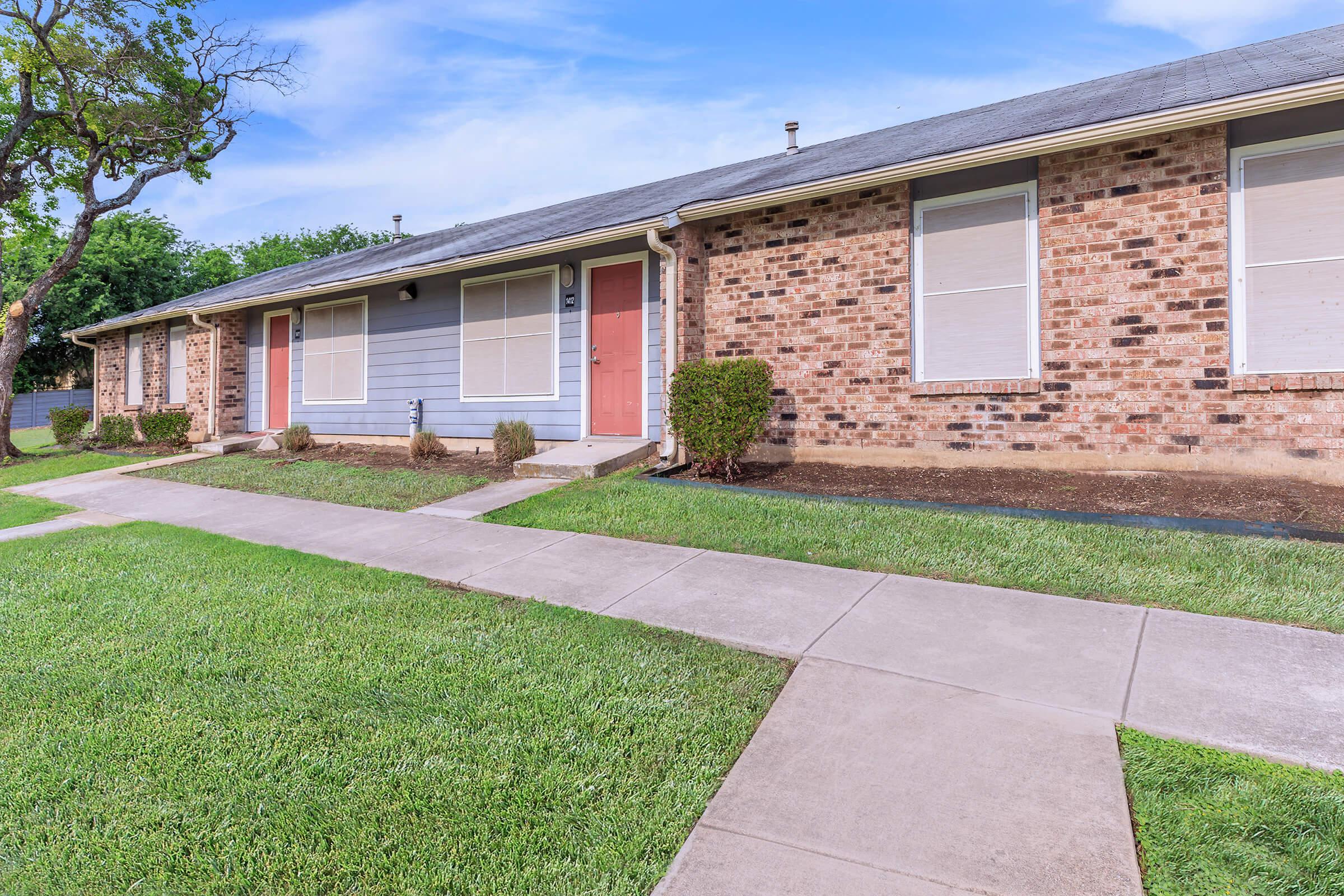 a house with a lawn in front of a brick building