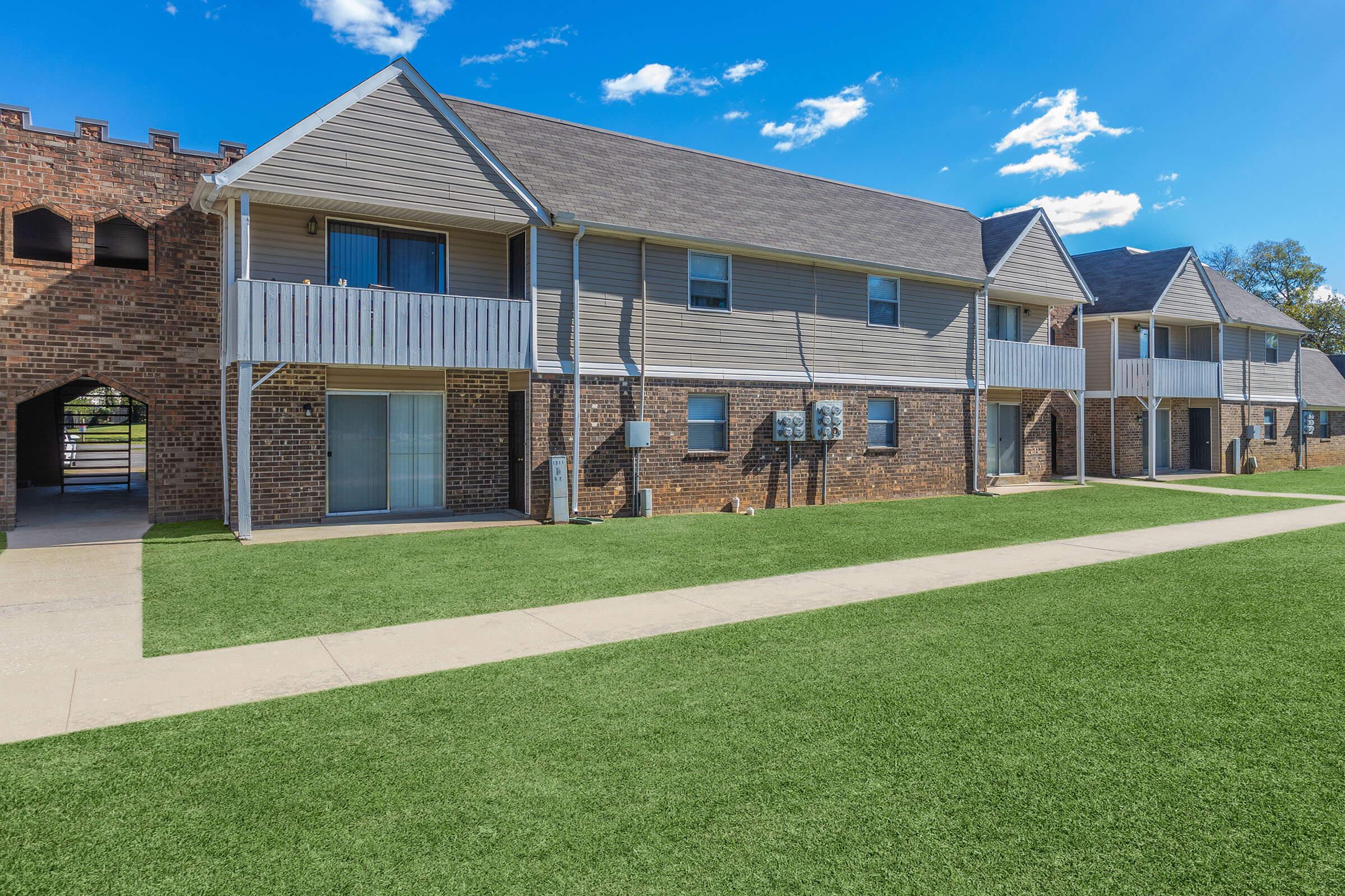 a large brick building with grass in front of a house