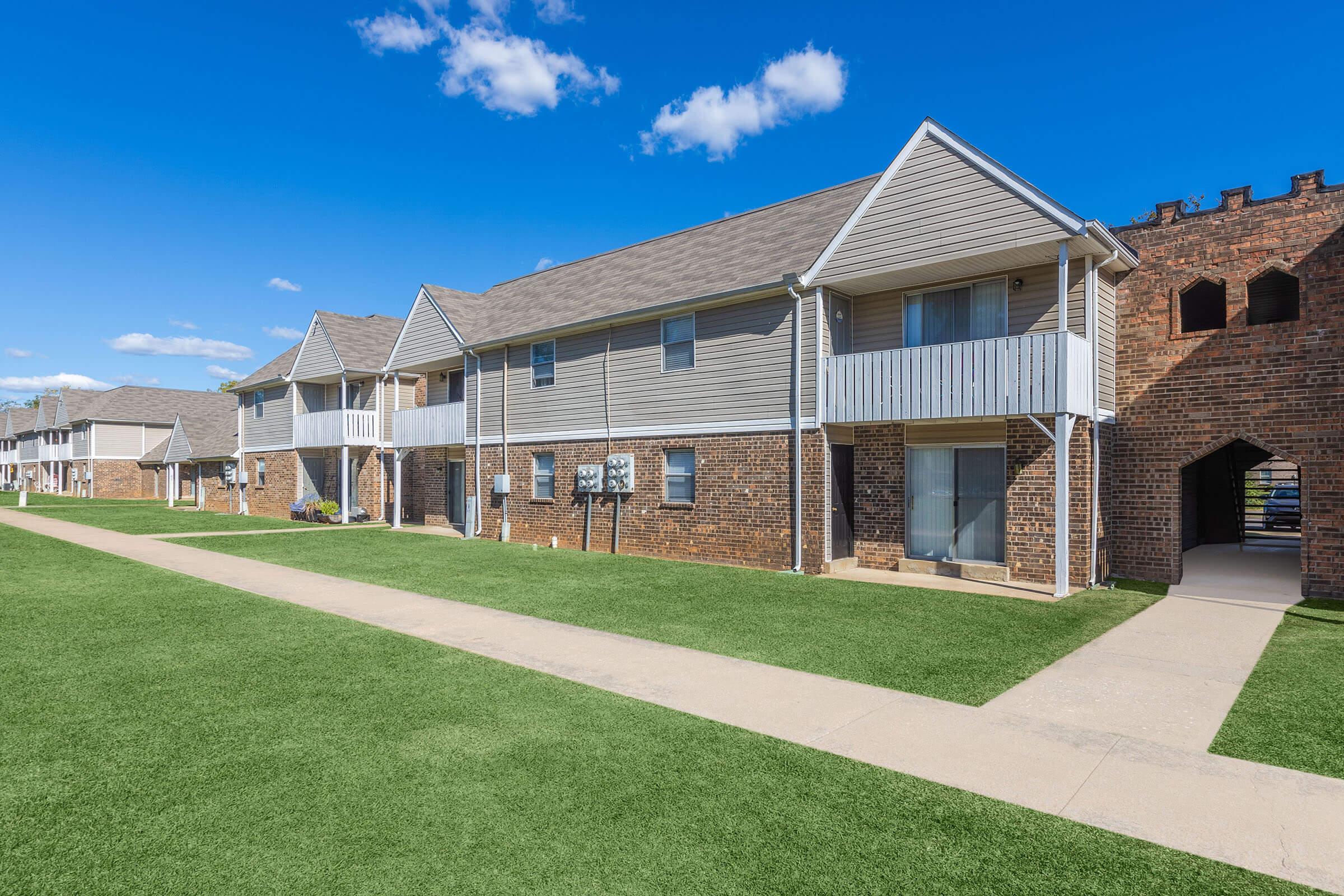 a large brick building with grass in front of a house