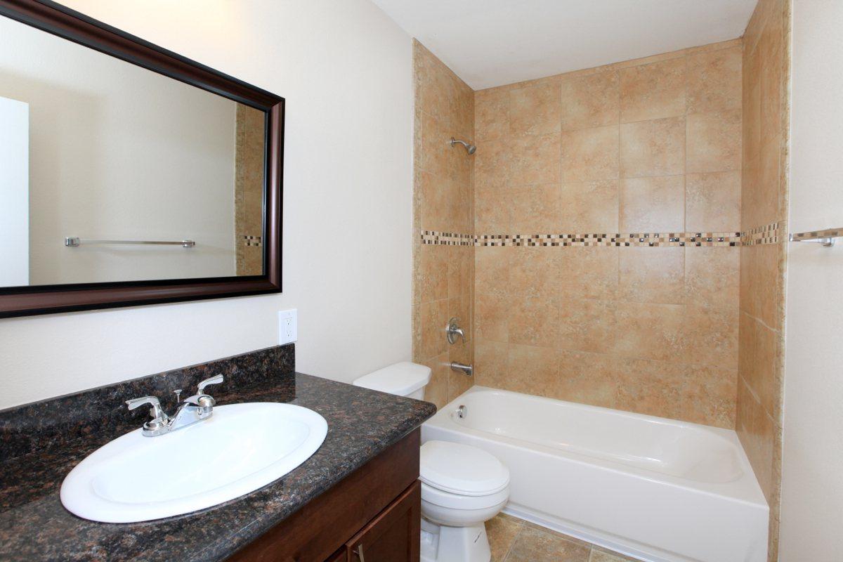 a white sink sitting under a mirror