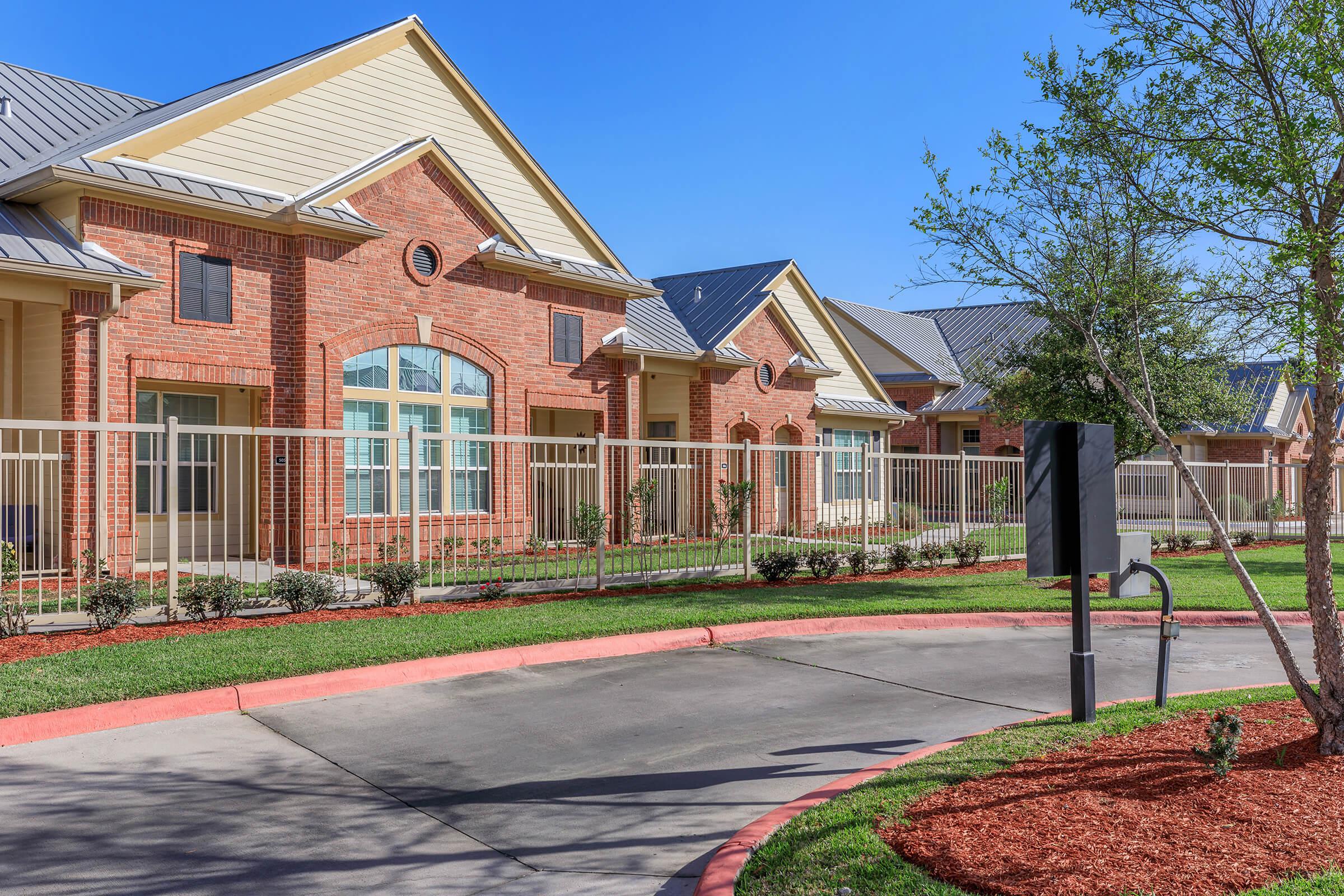 a large brick building with grass in front of a house