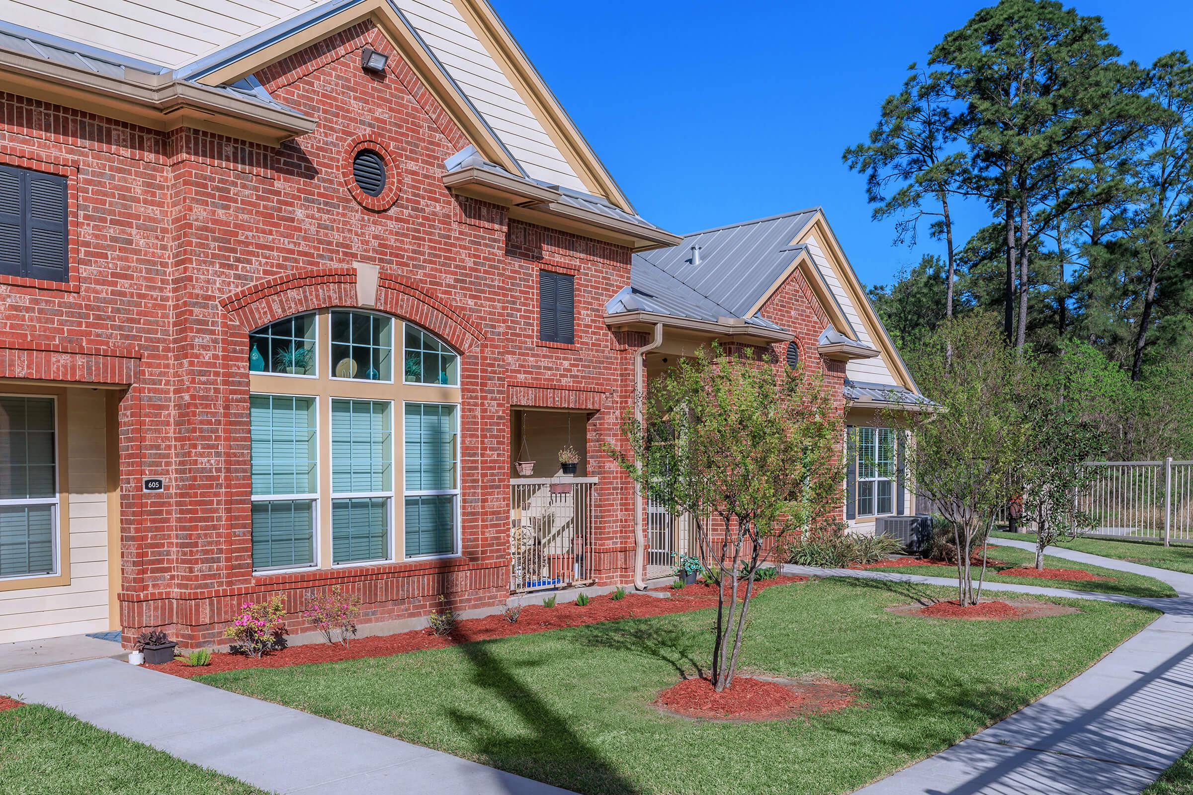 a large brick building with grass in front of a house