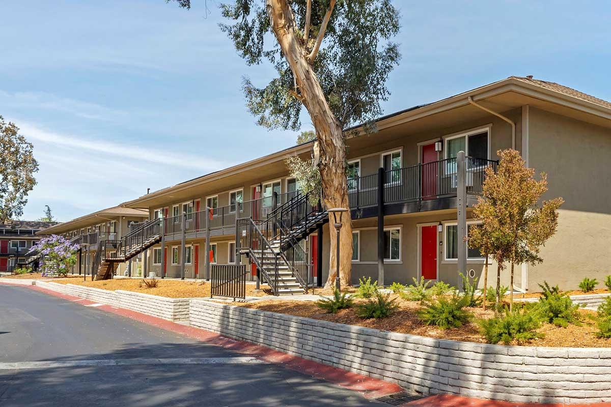 A row of low-rise apartment buildings with red doors and outdoor staircases.