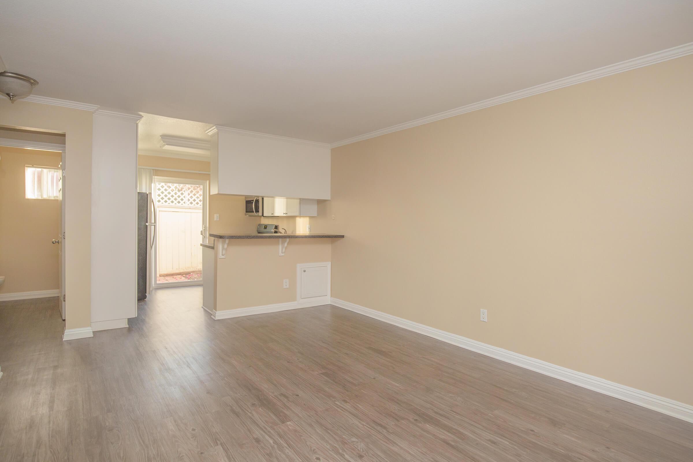 Vacant living room with kitchen in the background