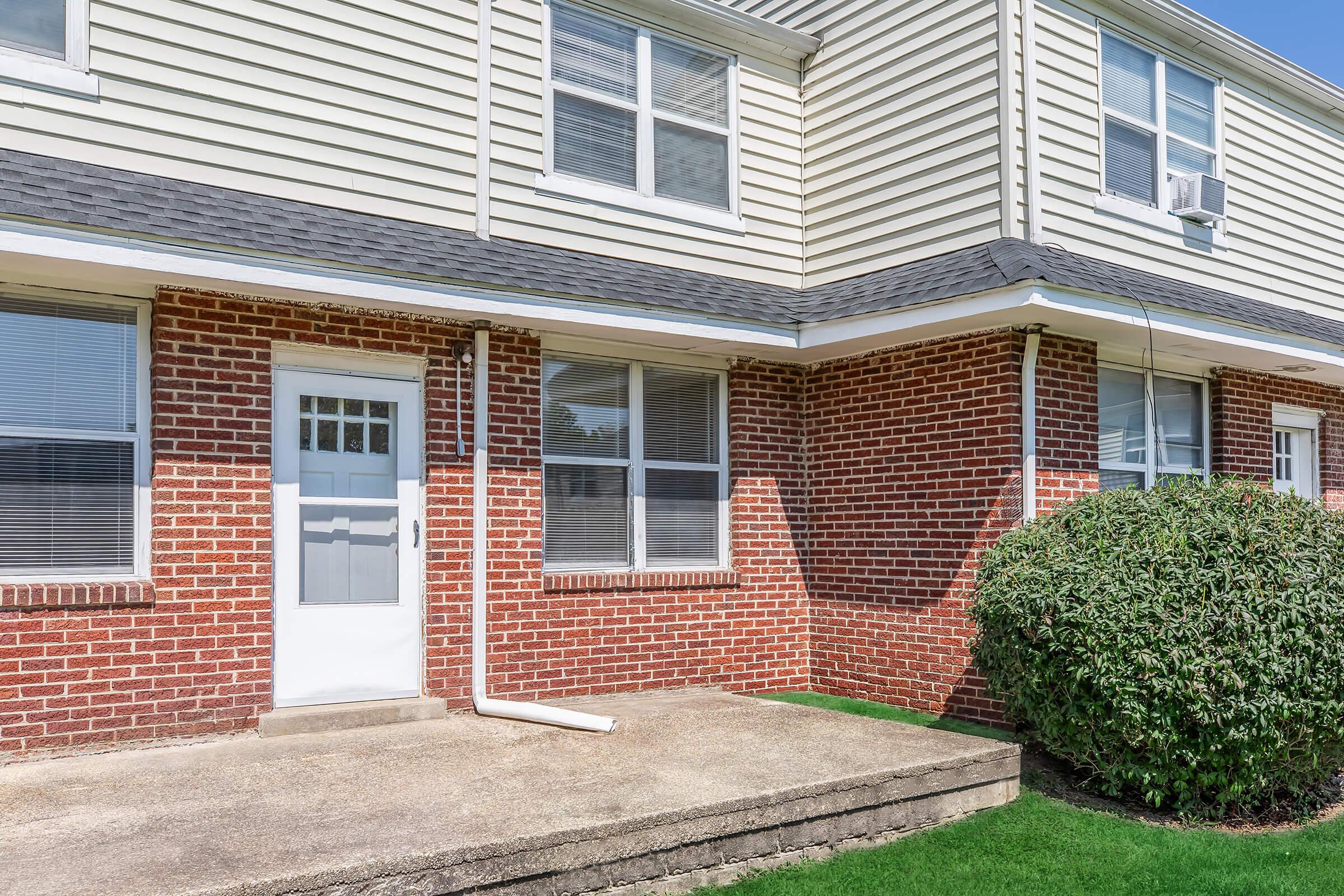 a large brick building with grass in front of a house