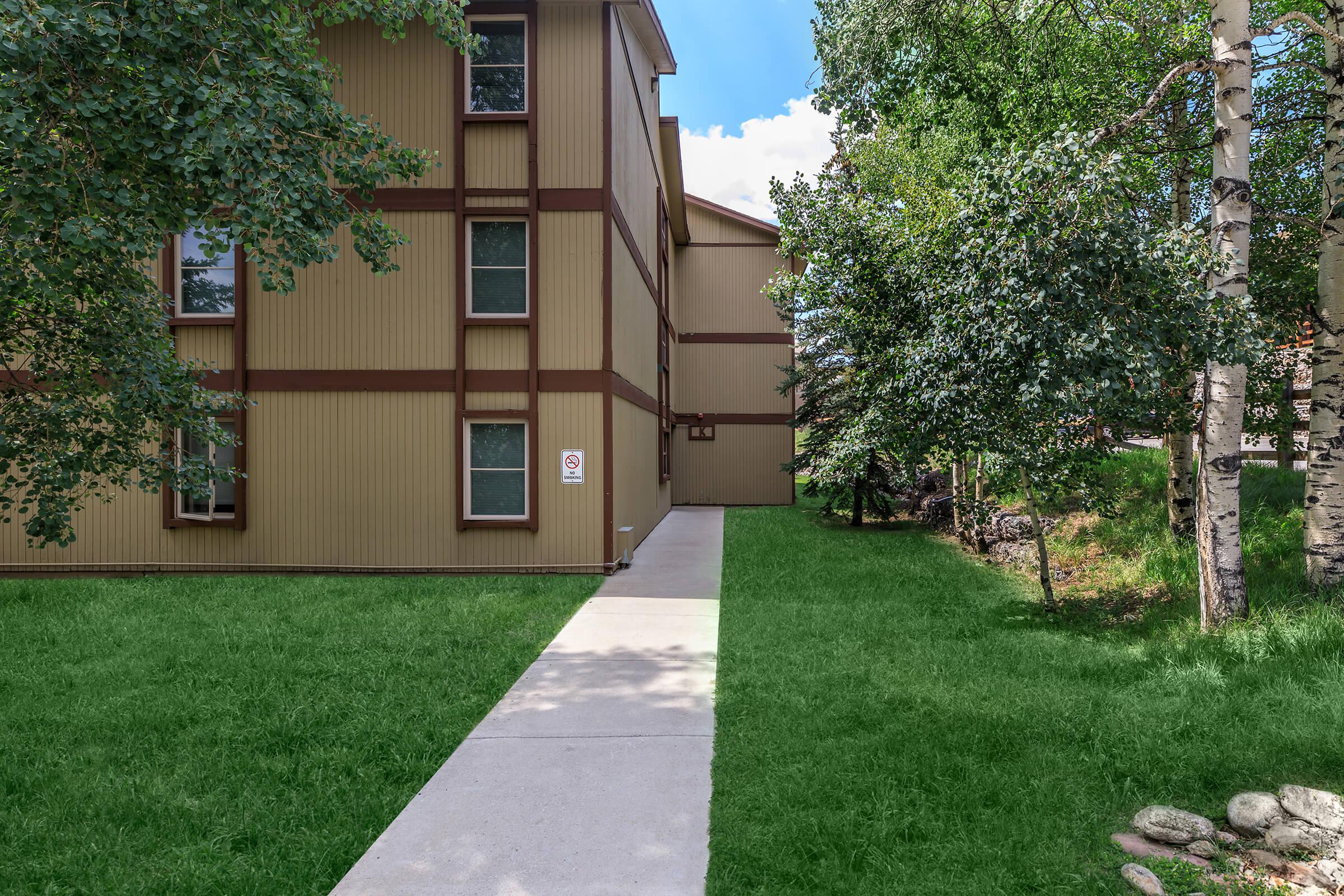 a house with a lawn in front of a brick building