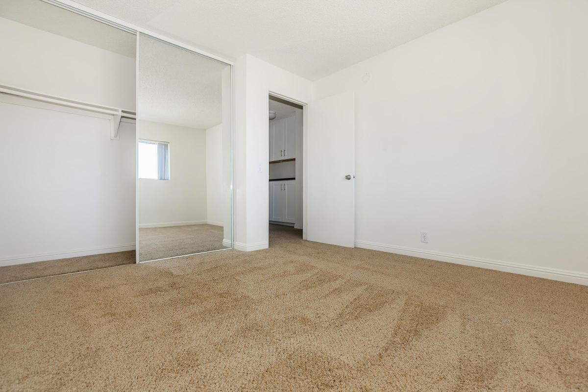 Unfurnished carpeted bedroom with sliding mirror glass closet door