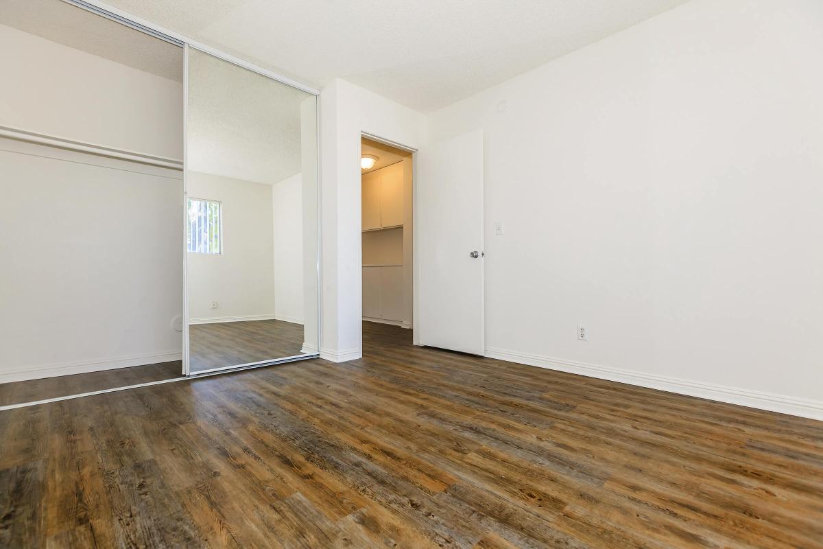 Unfurnished bedroom with open sliding mirror closet doors and wooden floors