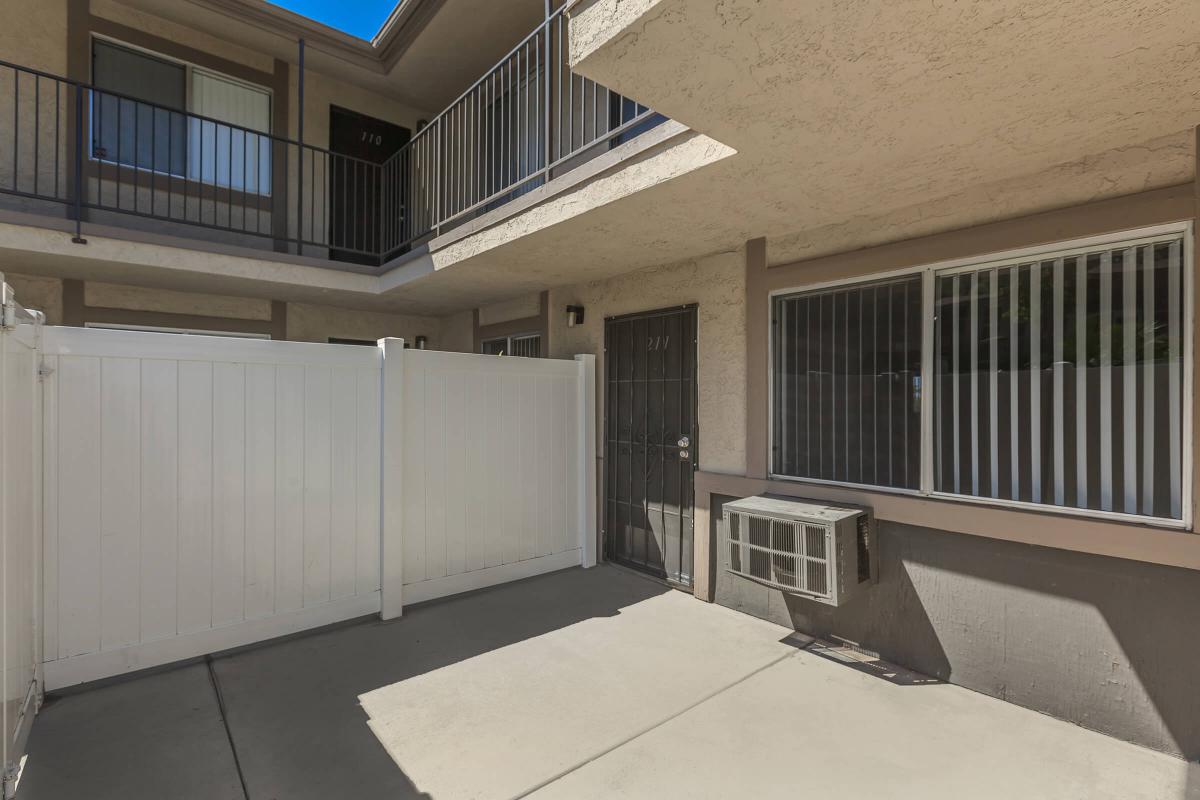 Unfurnished patio with a brown door and white fence