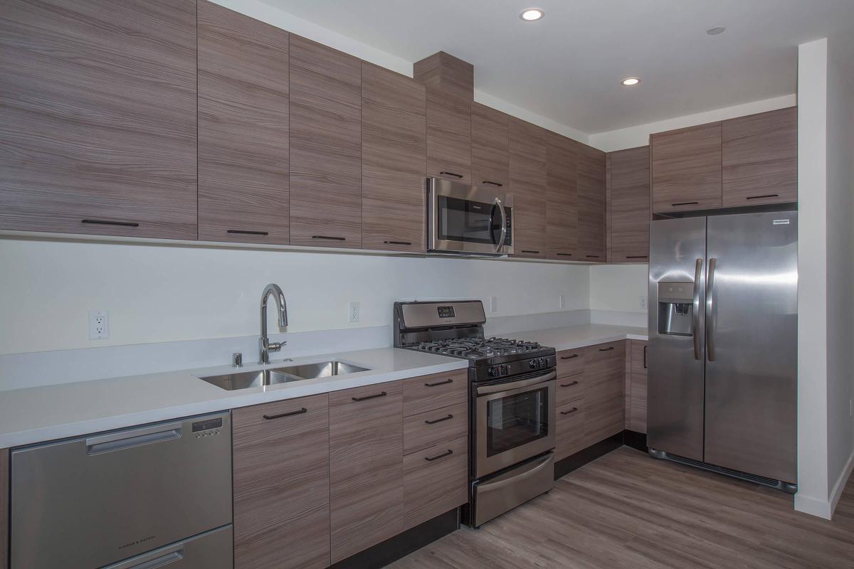 a large kitchen with stainless steel appliances and wooden cabinets