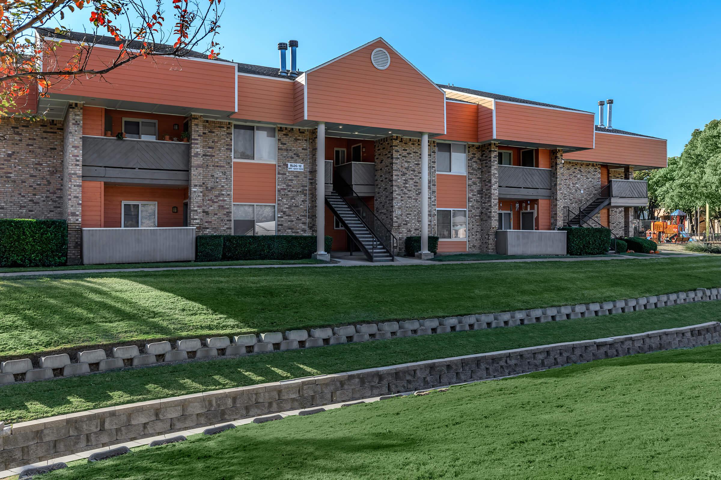 a large brick building with grass in front of a house