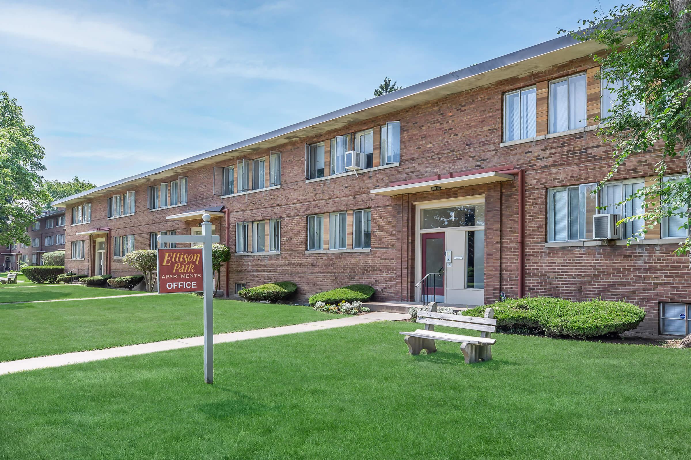 a house with a lawn in front of a brick building