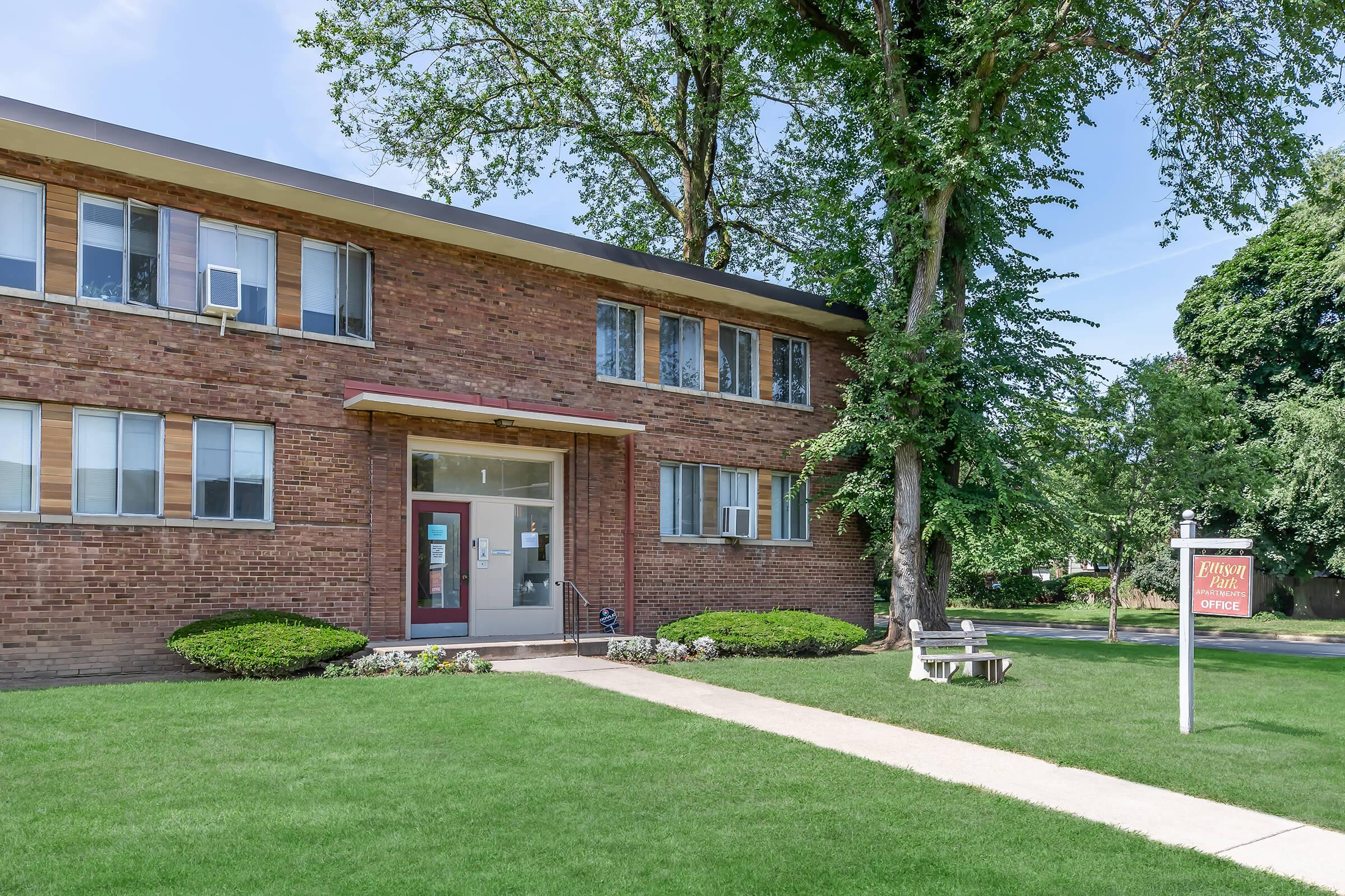 a house with a lawn in front of a brick building